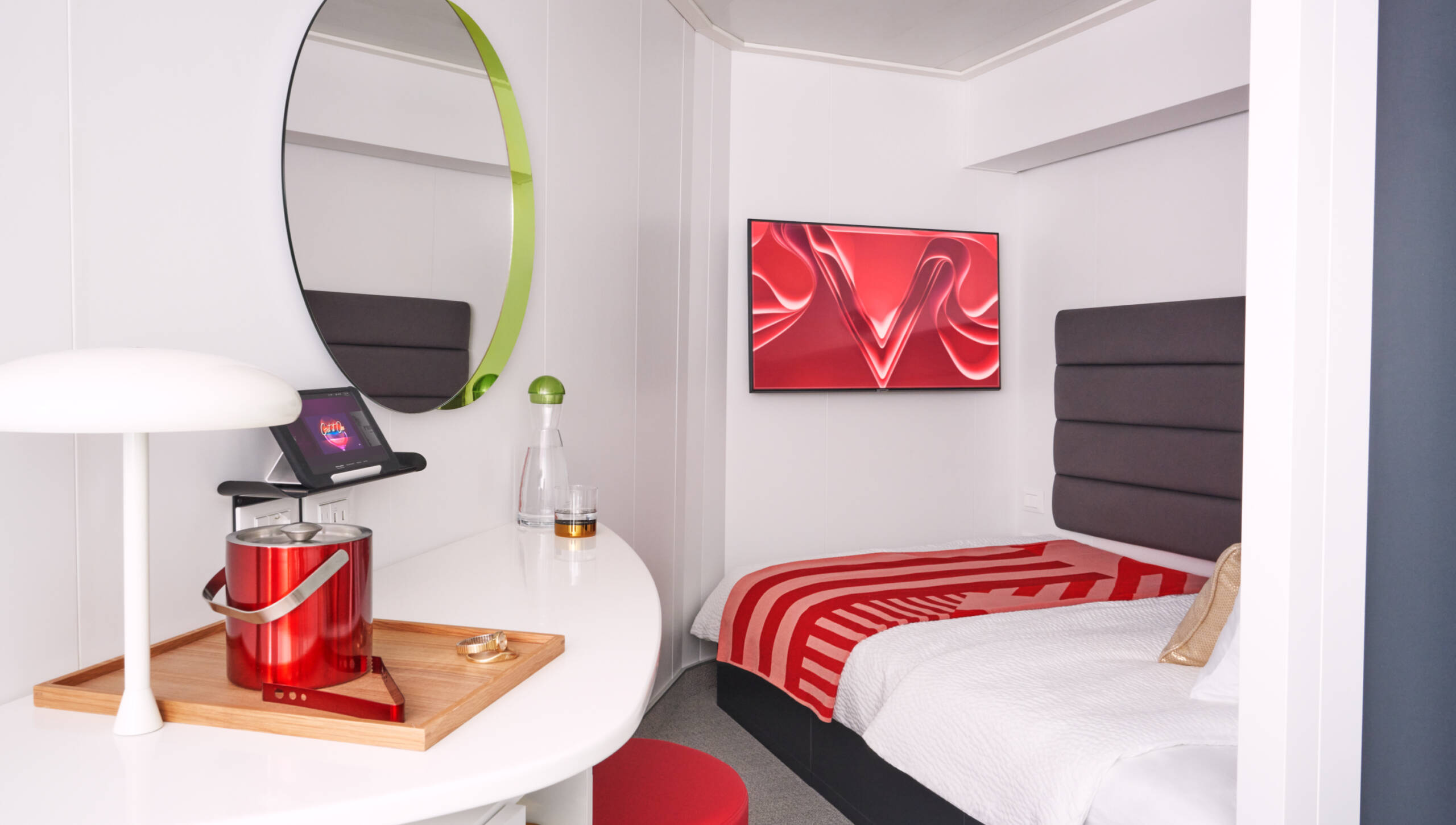 A white room with a single bed, mirror and vanity