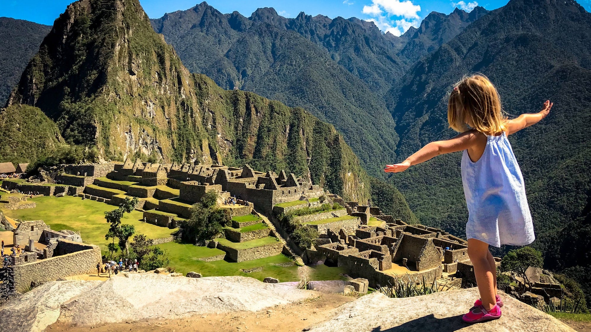 Full Length Of Girl Standing With Arms Outstretched On Rock At Mountain