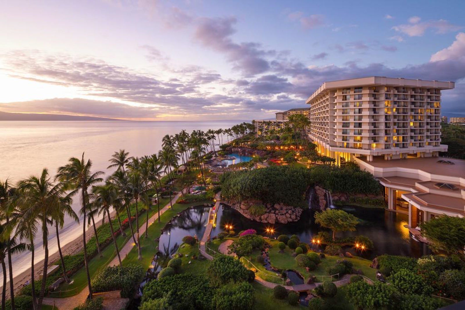 aerial photo of large hotel with lush gardens and pools at sunset