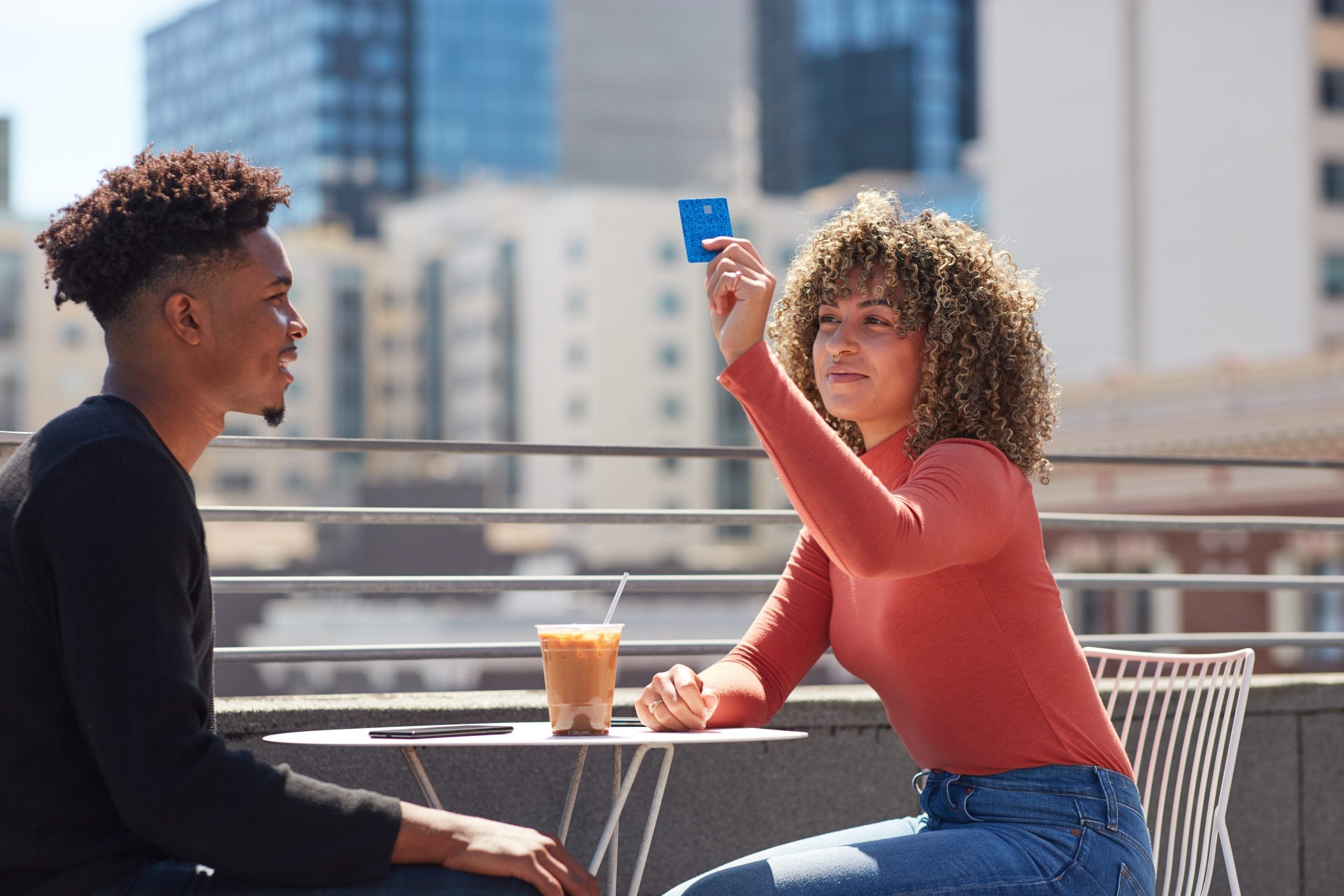A woman holding up the Venmo Credit Card to pay for her restaurant bill