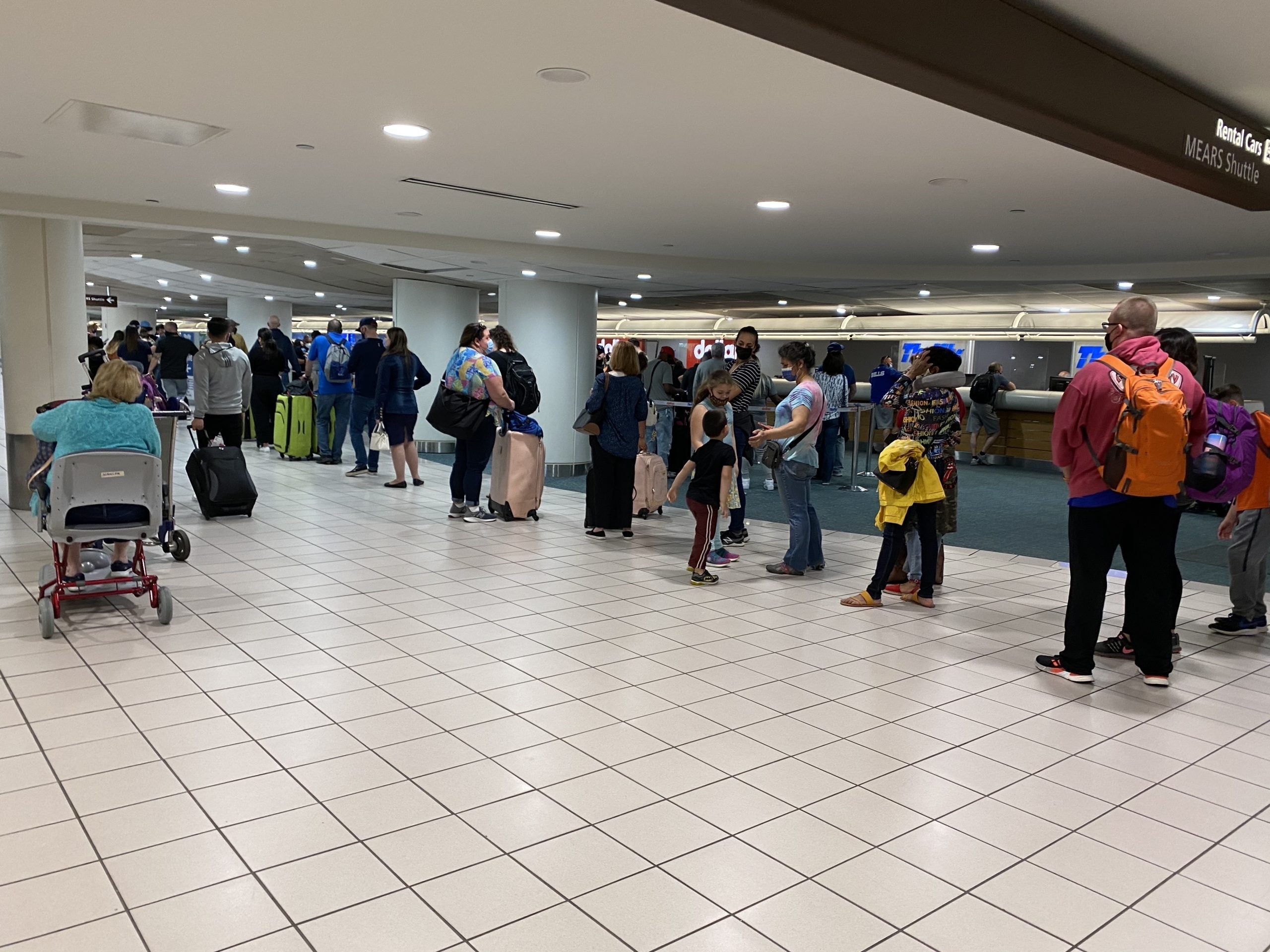 Several people waiting in line for a rental car at an airport
