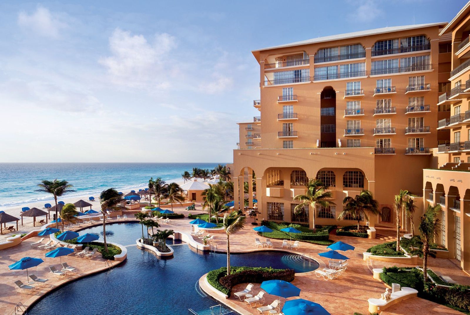 A hotel exterior and its swimming pool near the ocean