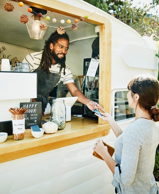Small business owner hands card back to customer.