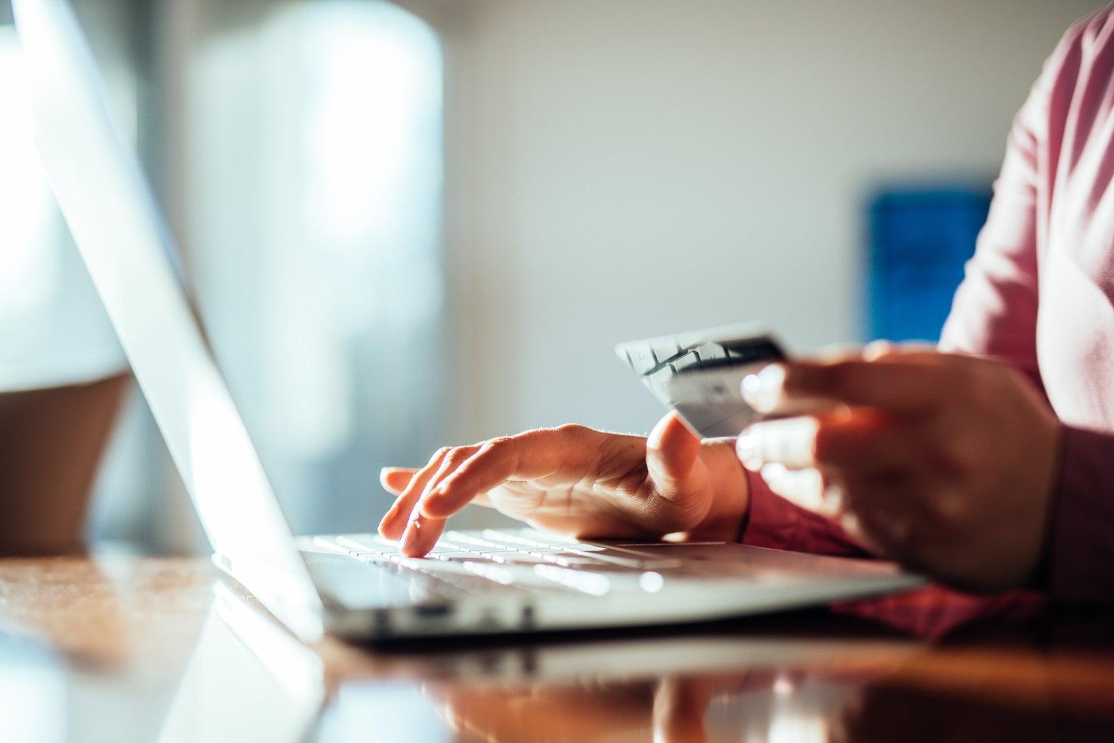 photo of person holding a credit card while typing on a laptop