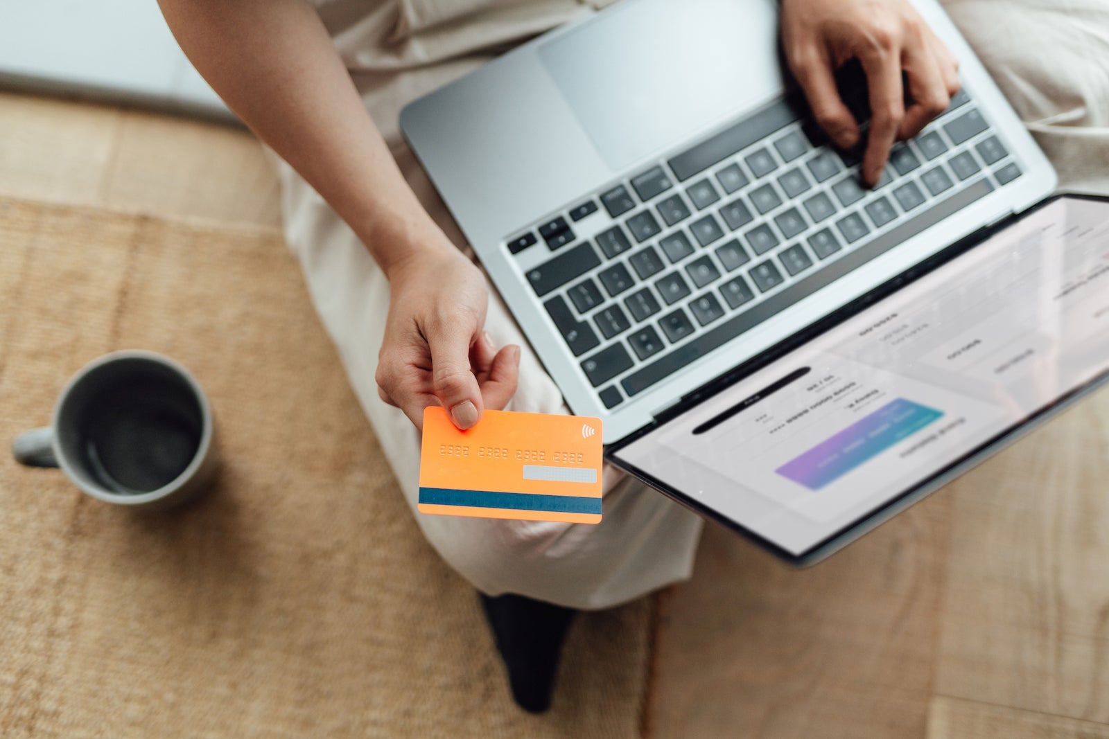 an unseen person holds a credit card while reading information on a laptop