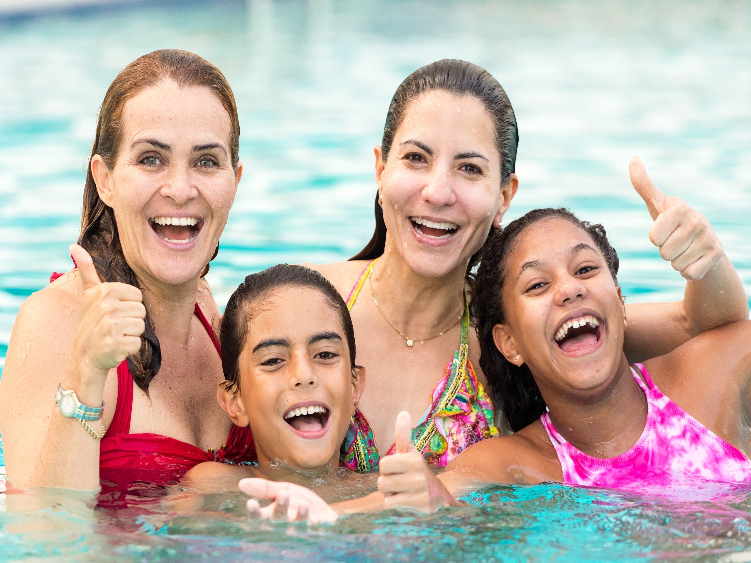 Two women in a pool with their children