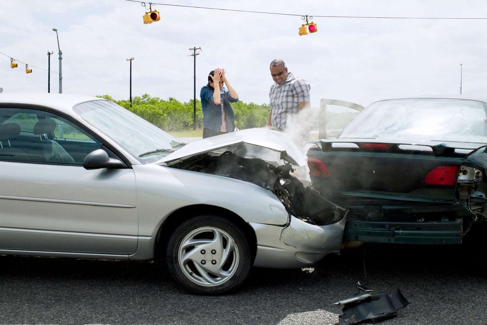 two people inspect their cars after a collision