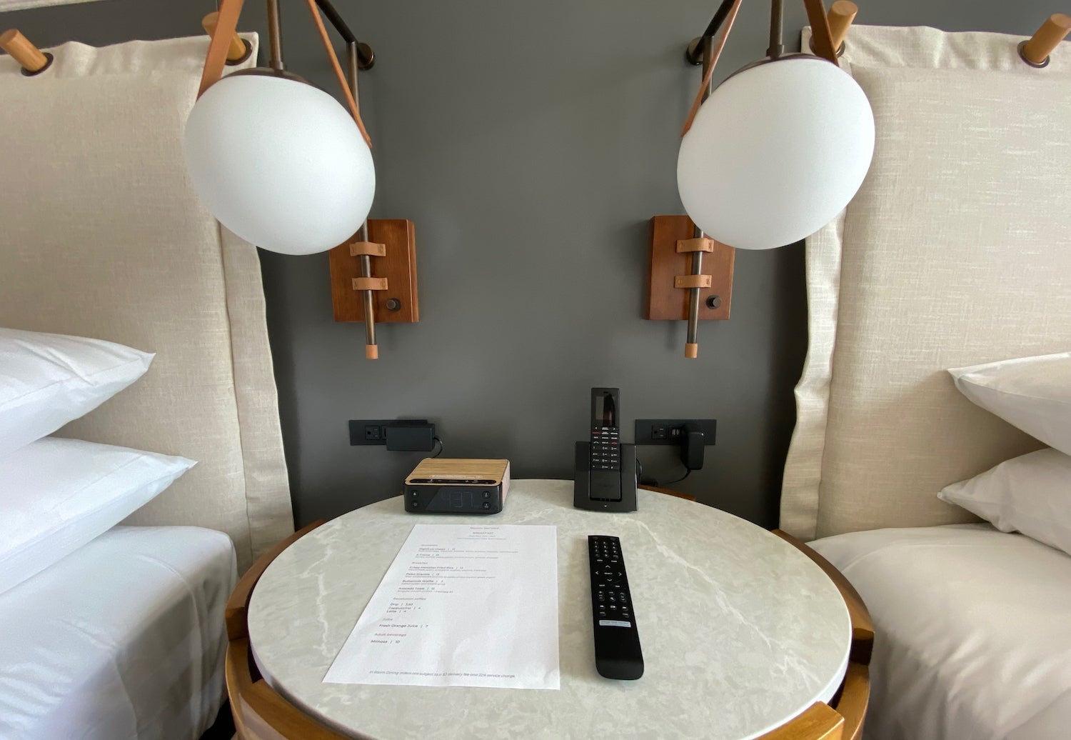 Hotel room nightstand with two light figures, an alarm clock and phone