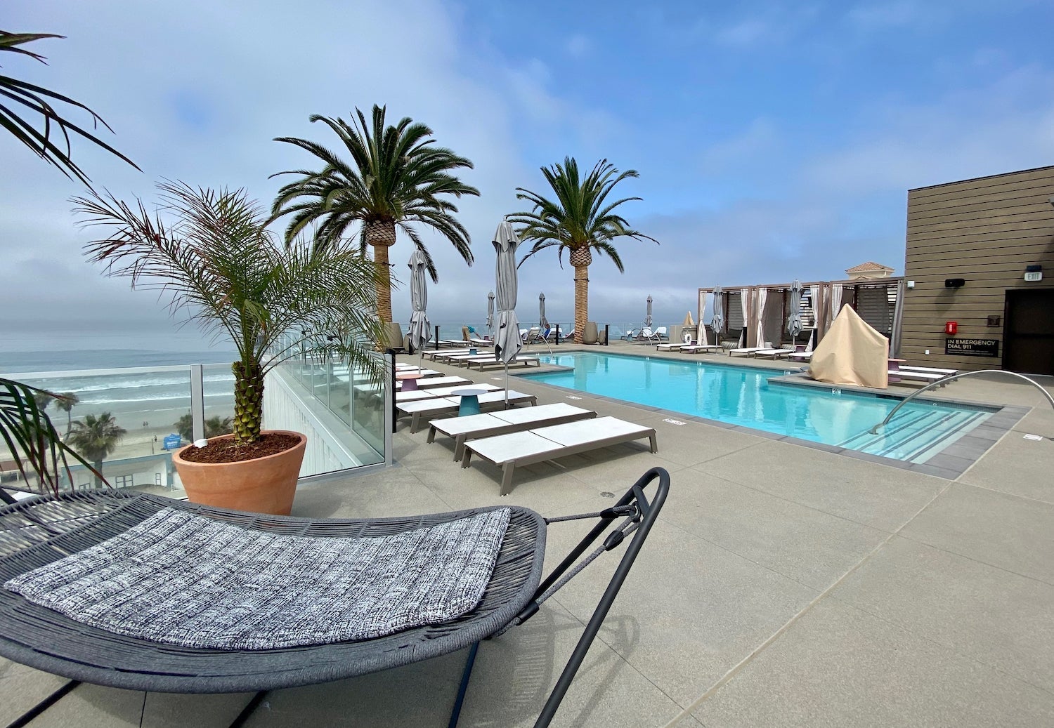Hotel pool surrounded by lounge chairs, cabanas and palm trees