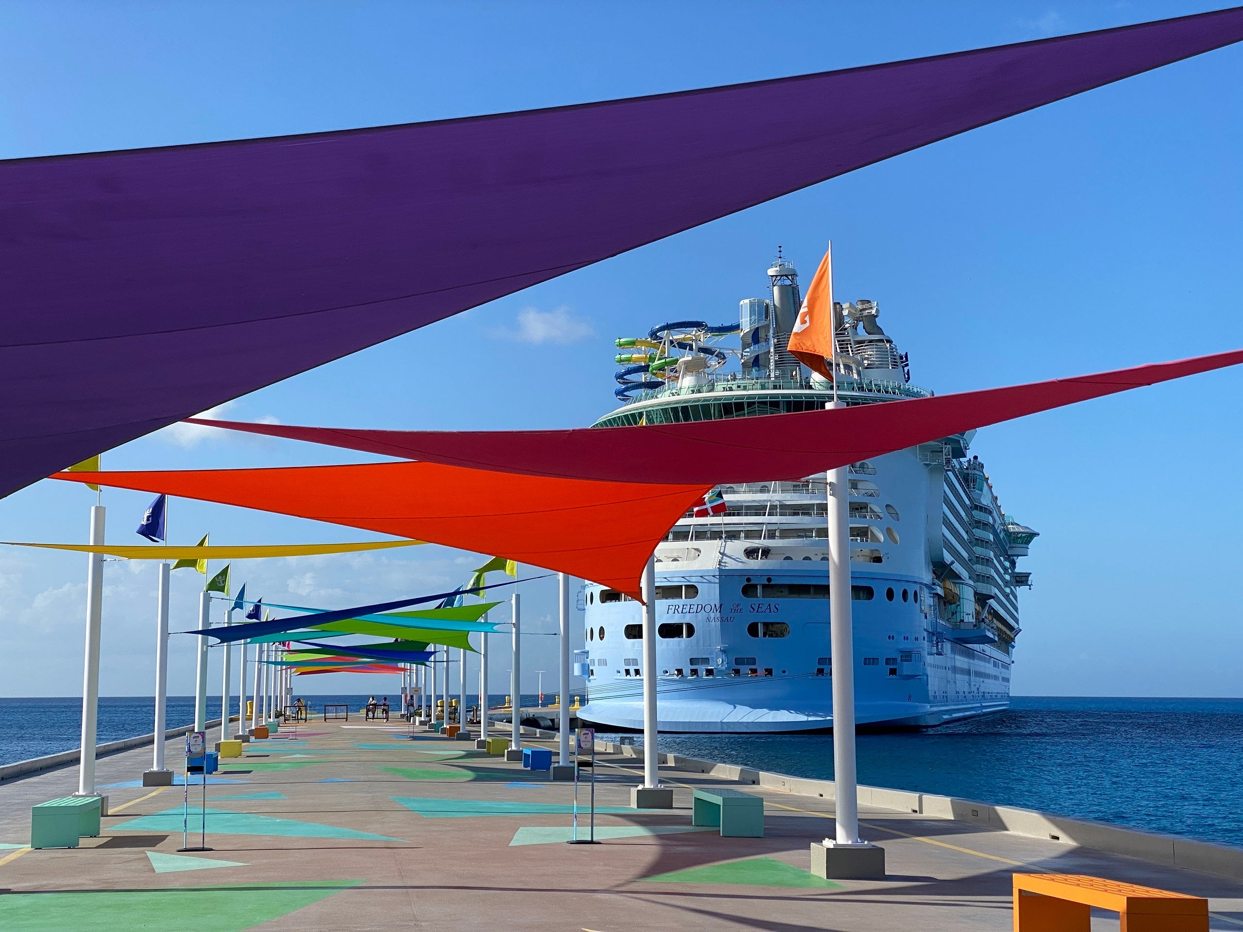 A Royal Caribbean cruise ship docked at private island Perfect Day at CocoCay near colorful awnings