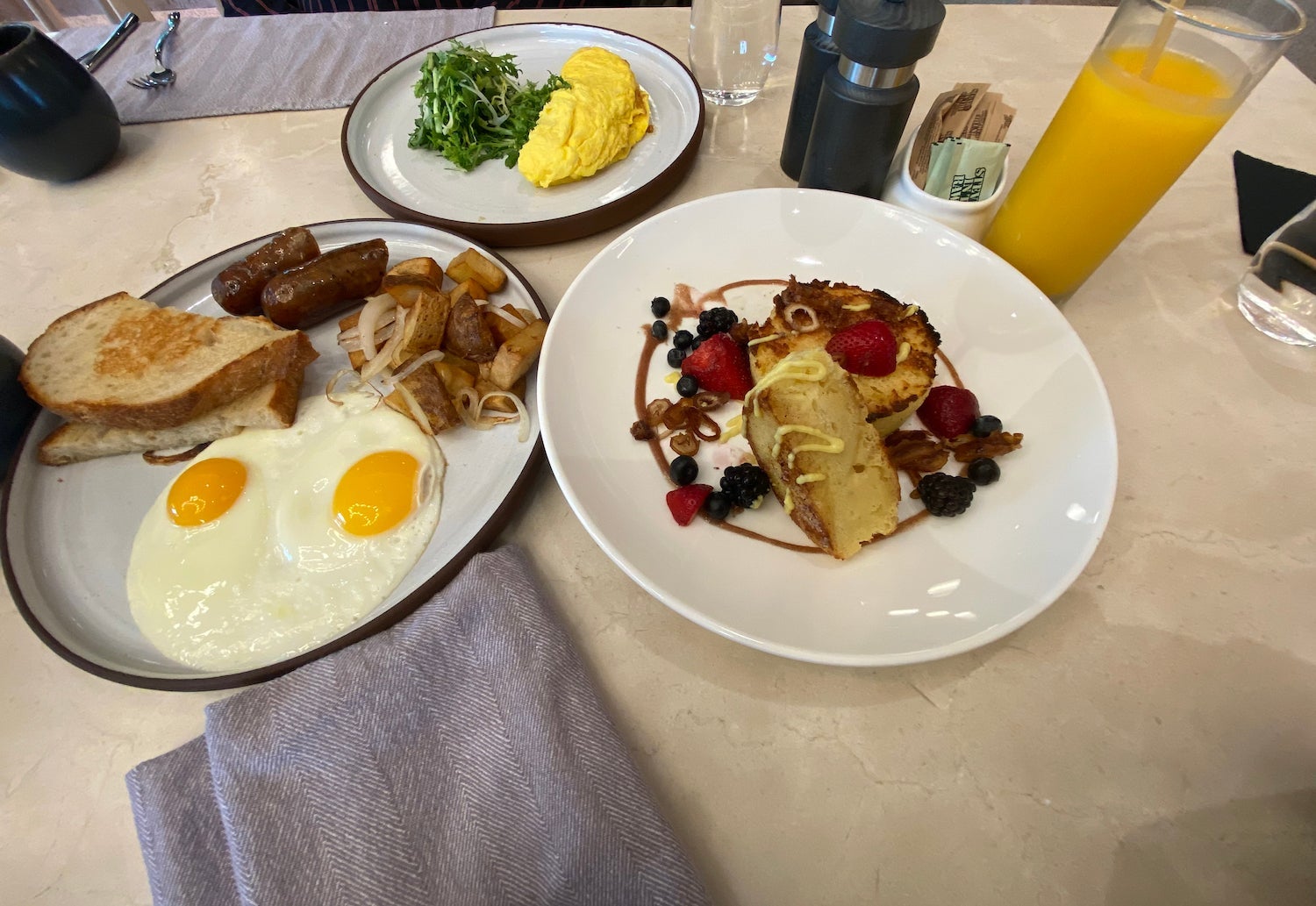 Omelette with french toast and a plate of eggs with bacon