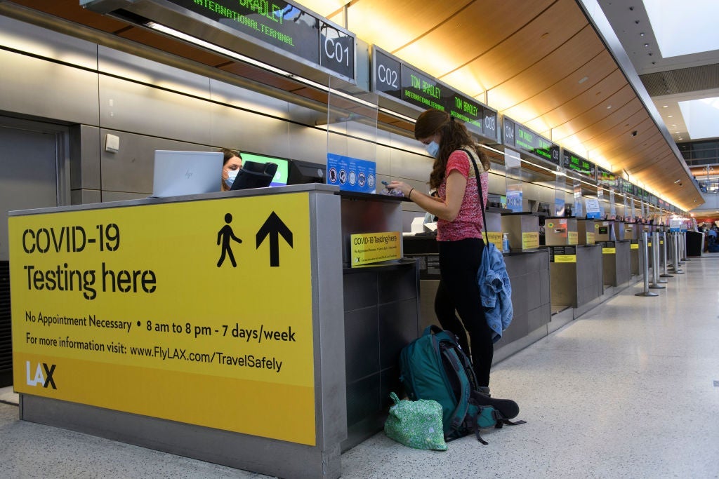 Mia Sloan checks the details of how to receive proof of her in-airport Covid-19 test results for a flight to Hawaii after being denied boarding earlier because her previous testing laboratory was not on Hawaii's list of approved labs during the Covid-19 pandemic at Los Angeles International Airport (LAX) in Los Angeles, California, November 18, 2020. (Photo by Patrick FALLON / AFP) (Photo by PATRICK FALLON/AFP via Getty Images)