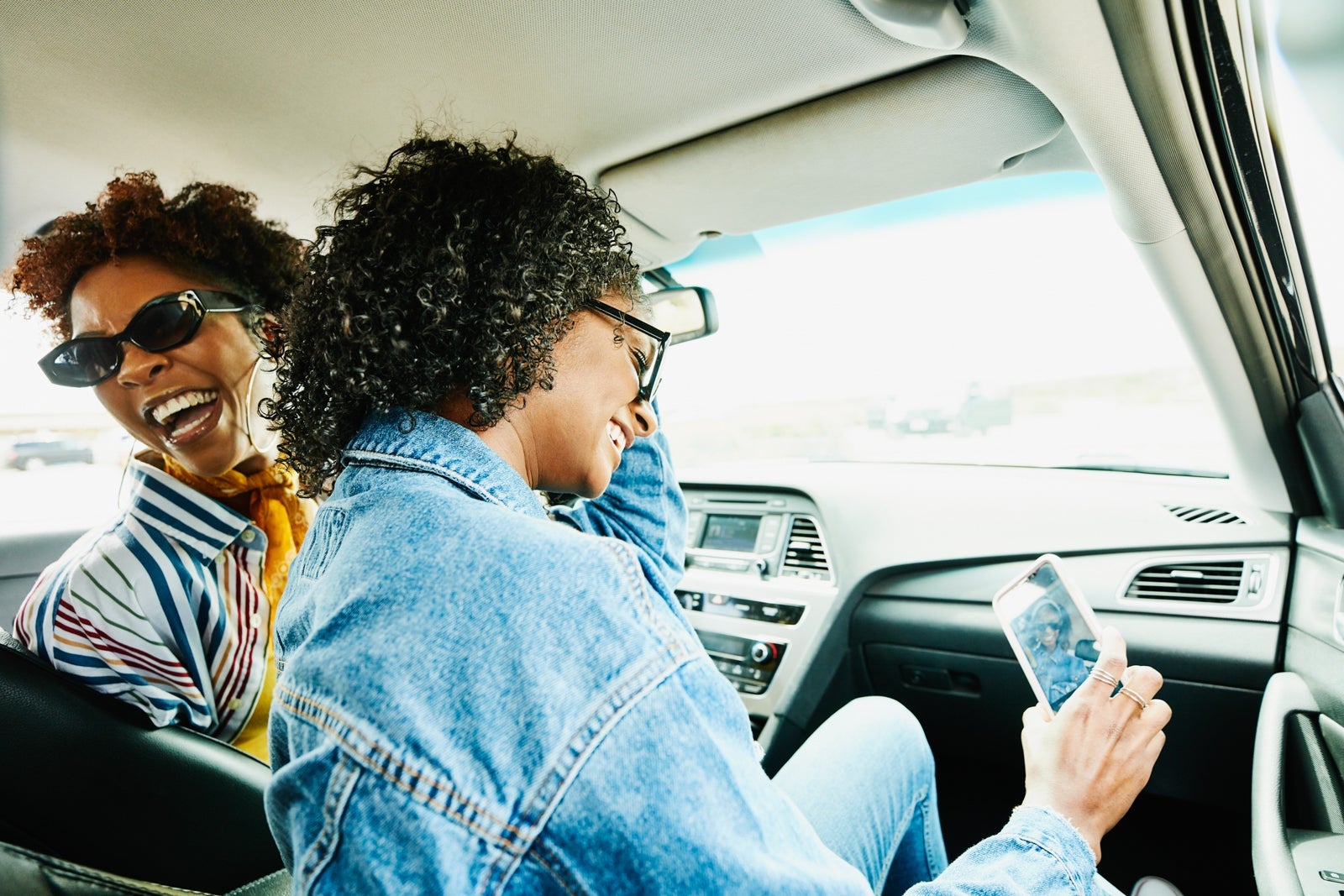 view from the backseat of a car showing 2 people in the front seats