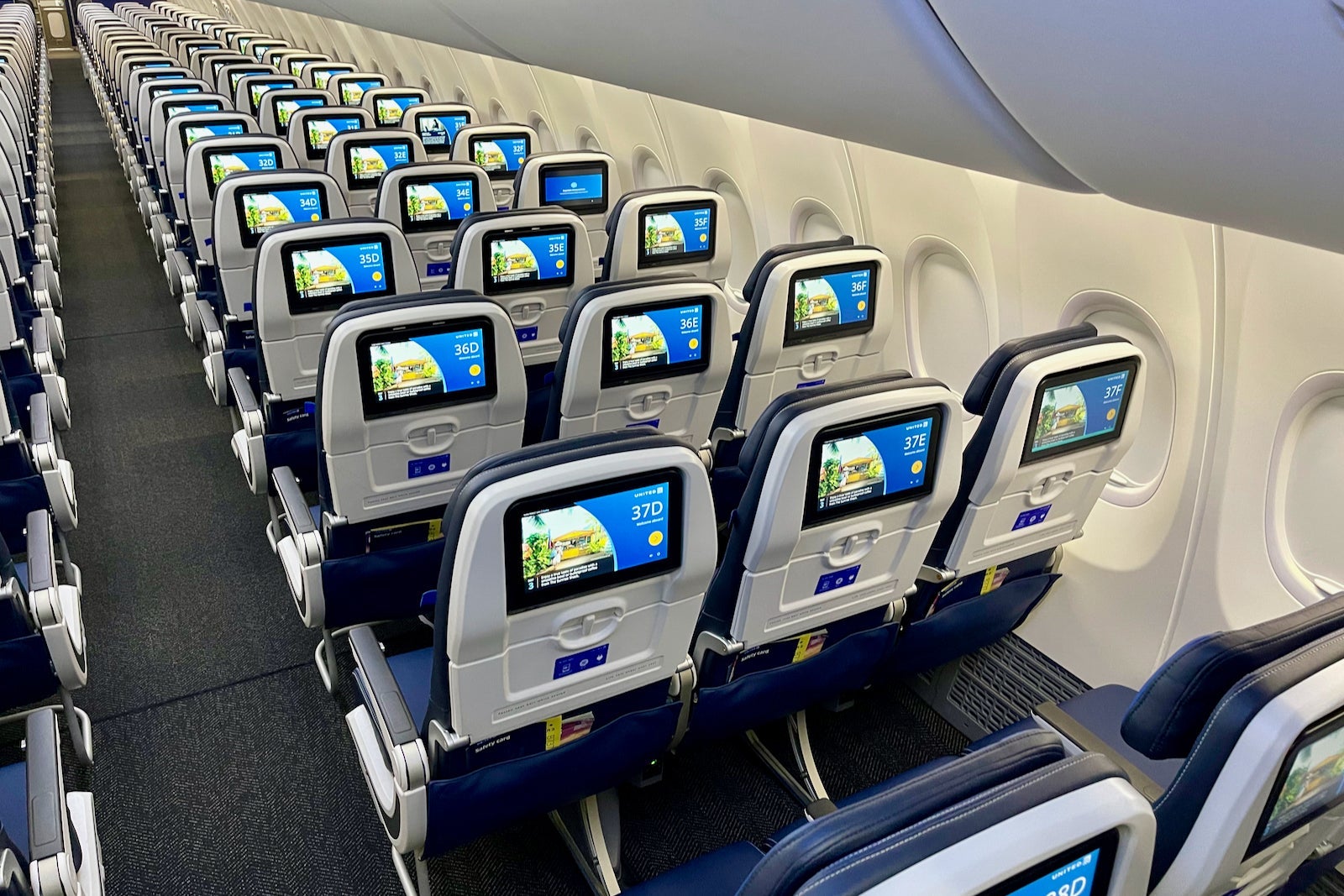 rows of airplane seats with seatback screens