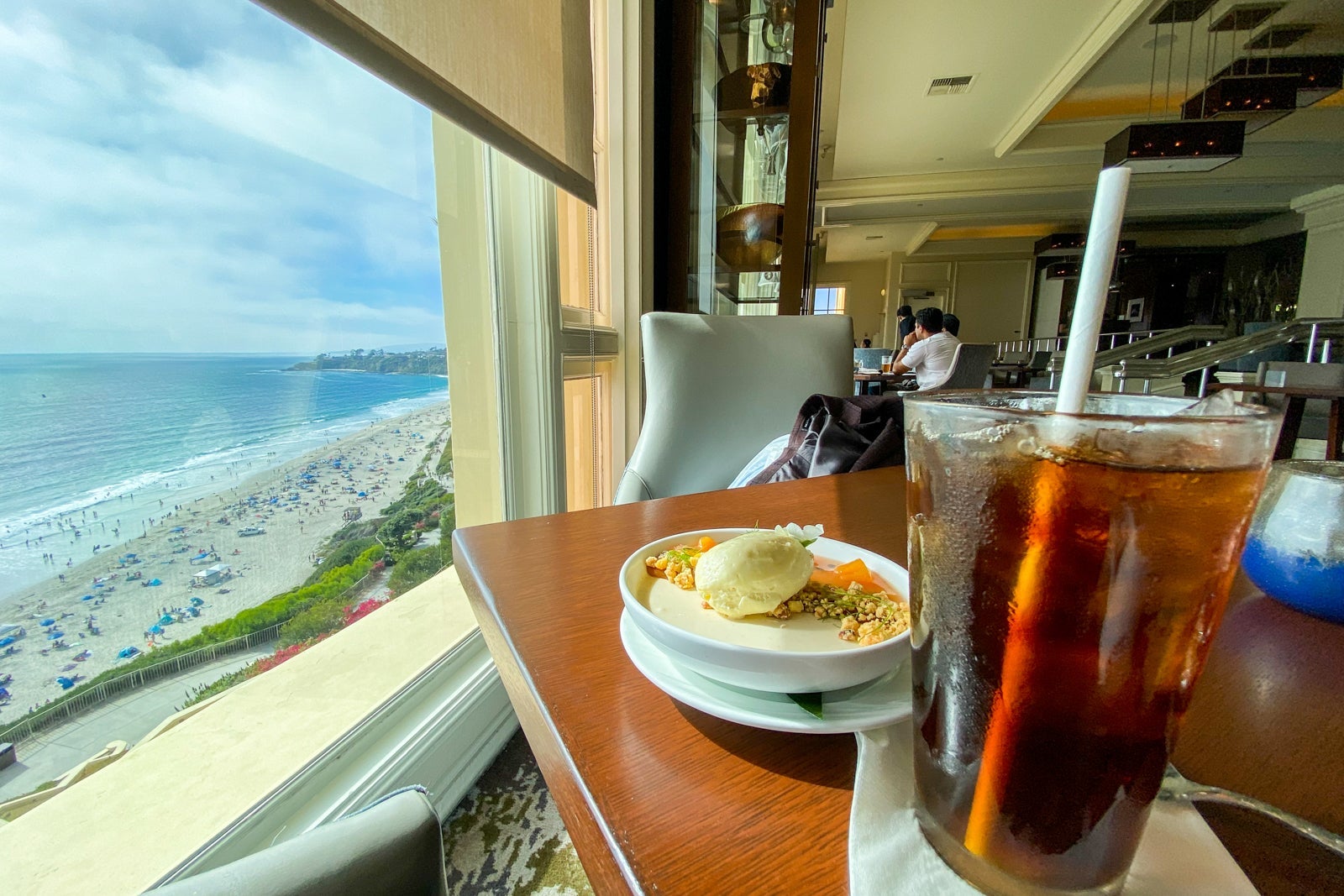 Restaurat table with iced coffee and pana cotta facing a beach