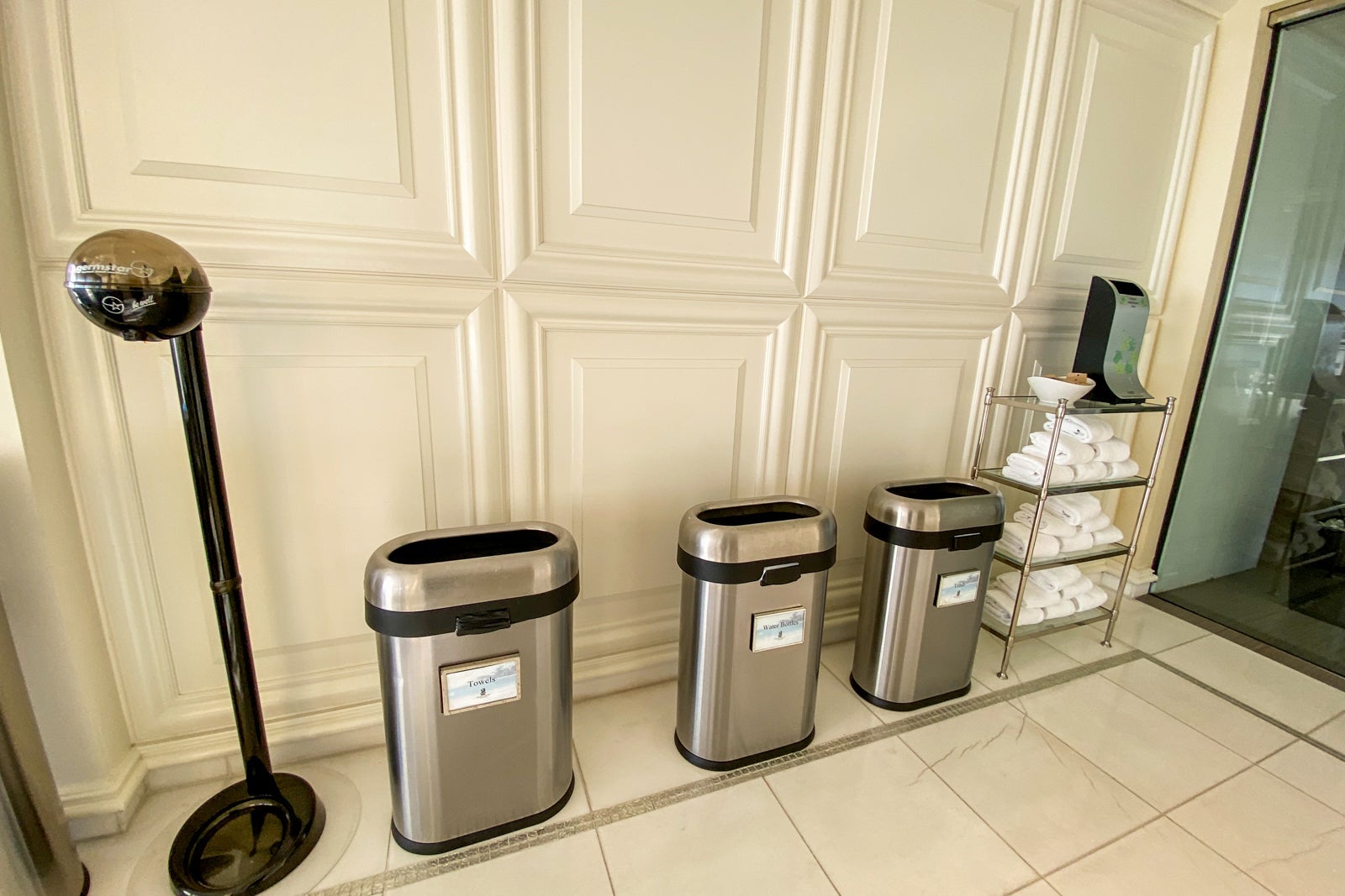 Hand sanitizer dispenser next to two container and a towel rack
