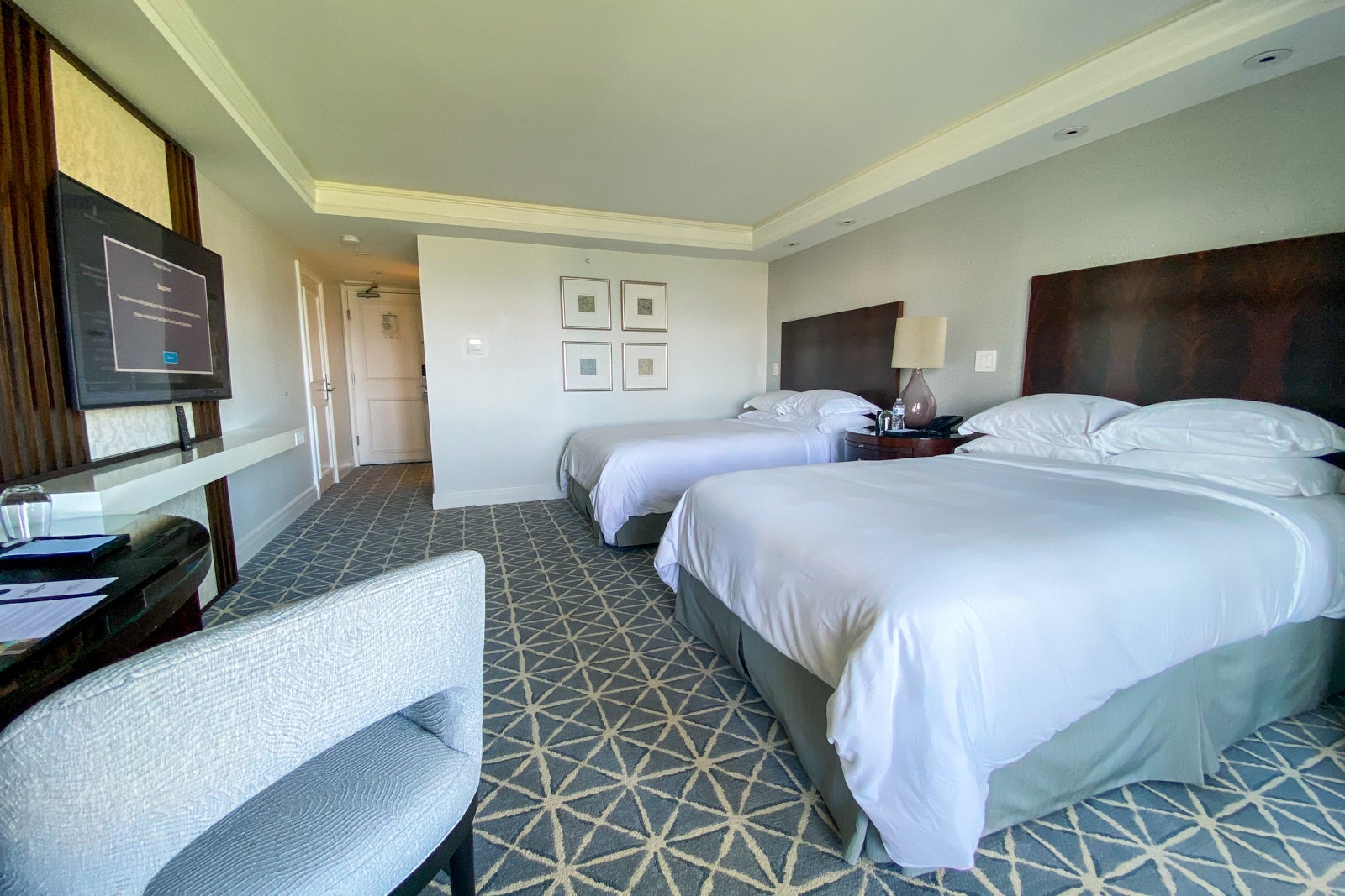 Two double beds facing a desk, with blue carpet