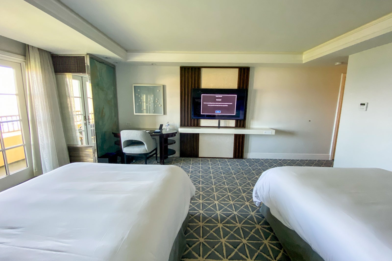 Two double beds facing a desk and tv