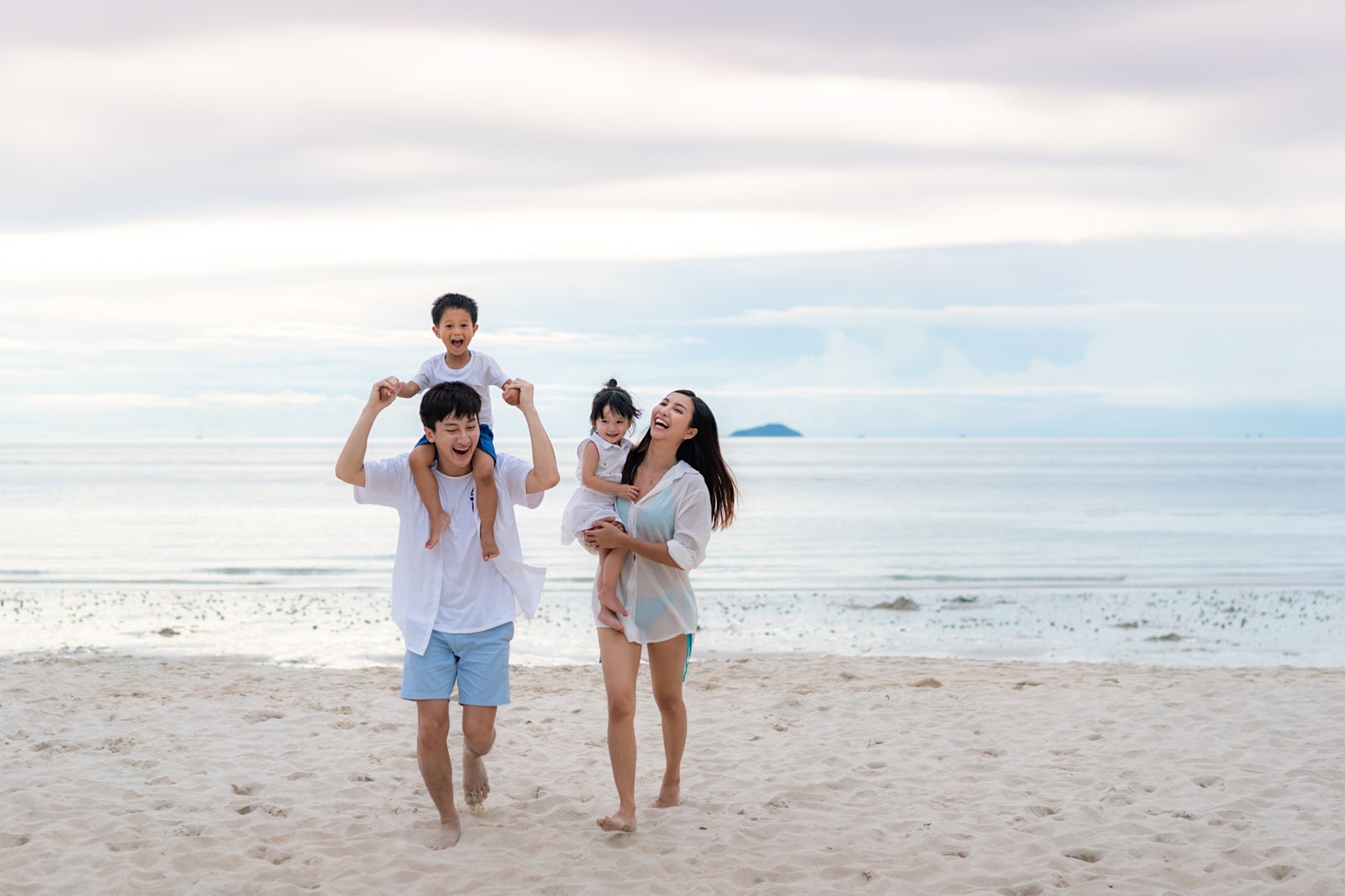 Happy Asian family walking on the beach