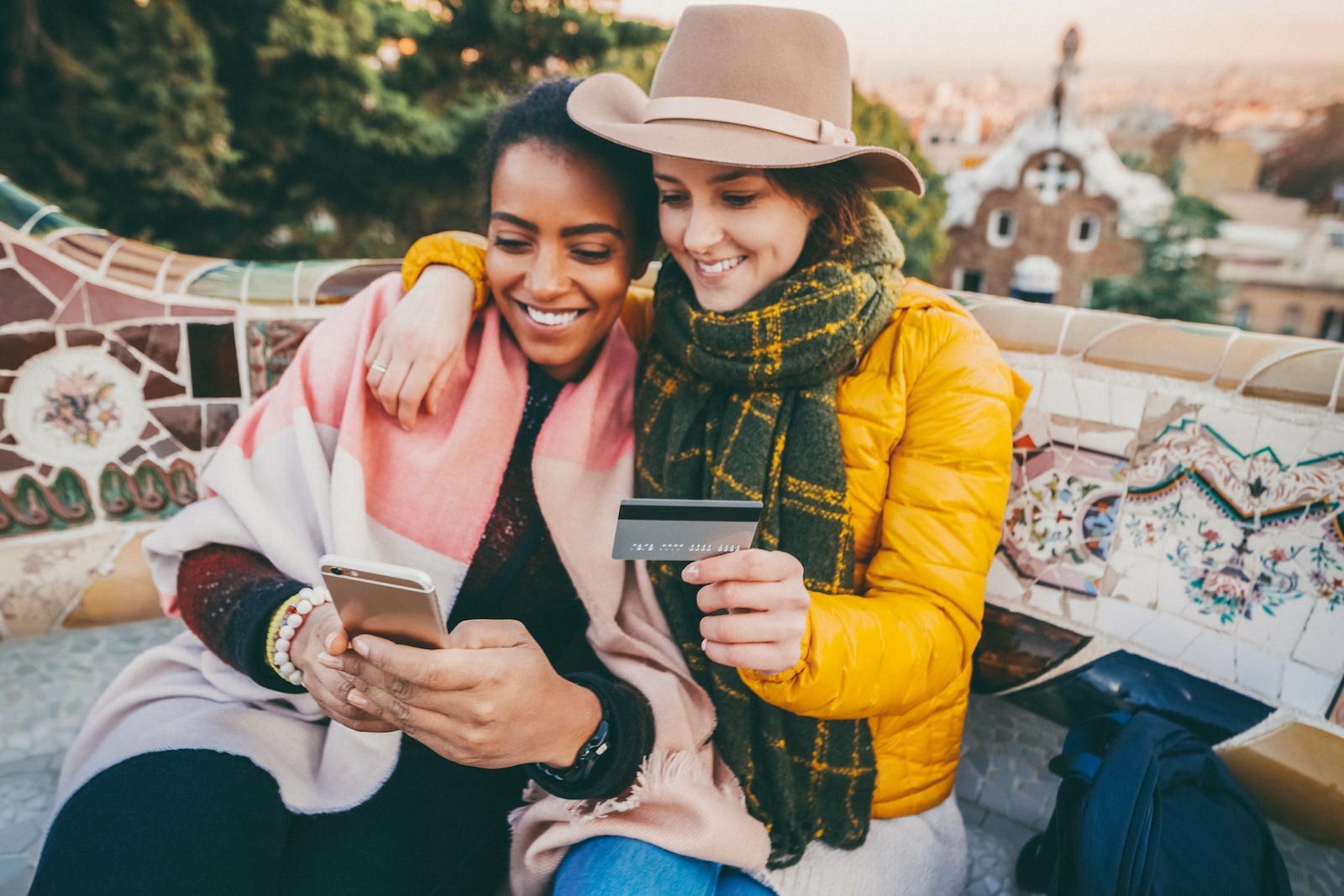 Two friends use a credit card to make a purchase through a smart phone