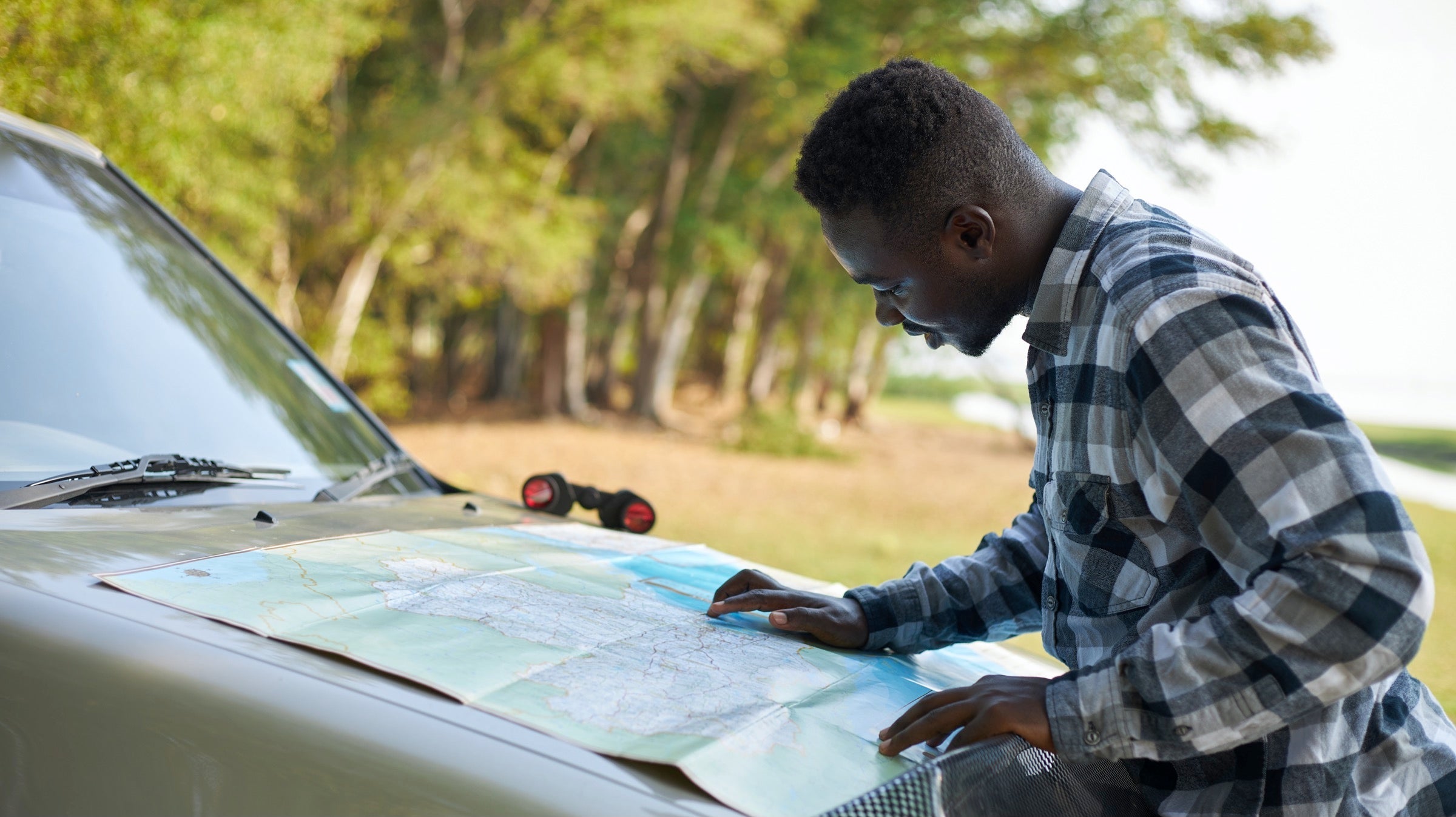 Man looking at a map on the front of a car