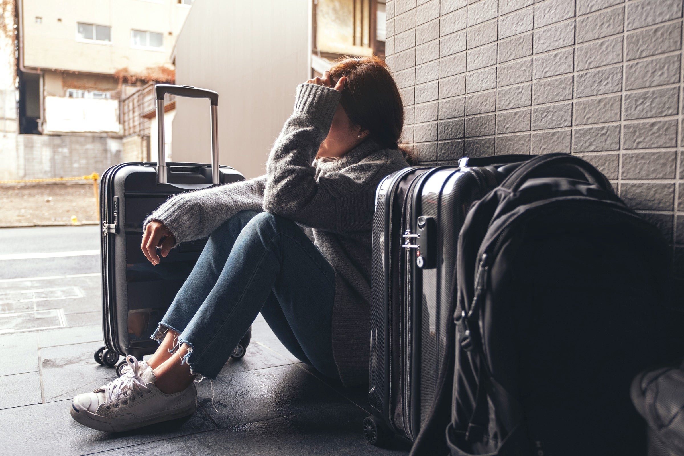 Sad traveler with multiple suitcases and a backpack
