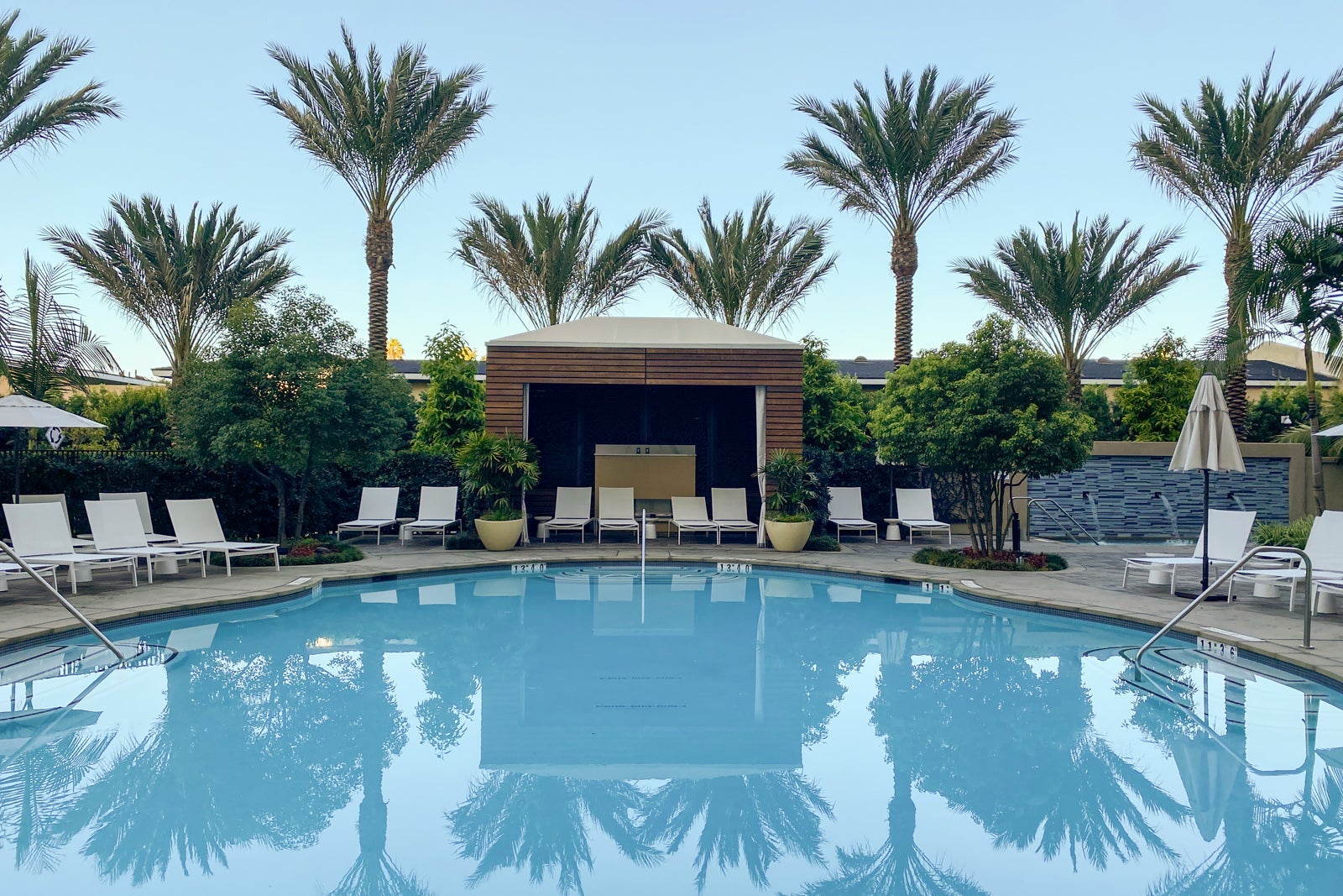 a hotel pool surrounded by lounge chairs and palm trees