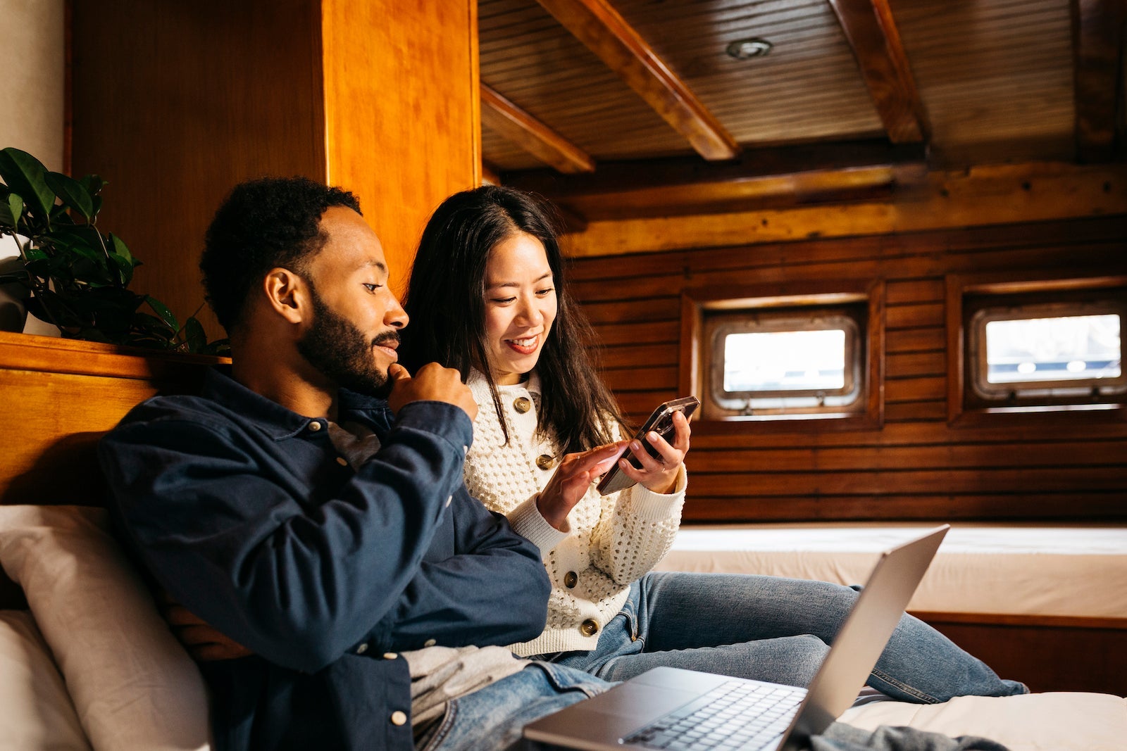 Reasons to get the Ink Business Preferred over the Sapphire Reserve Young mixed race couple using on a laptop sitting on a bed in a cabin of a vintage sailing boat
