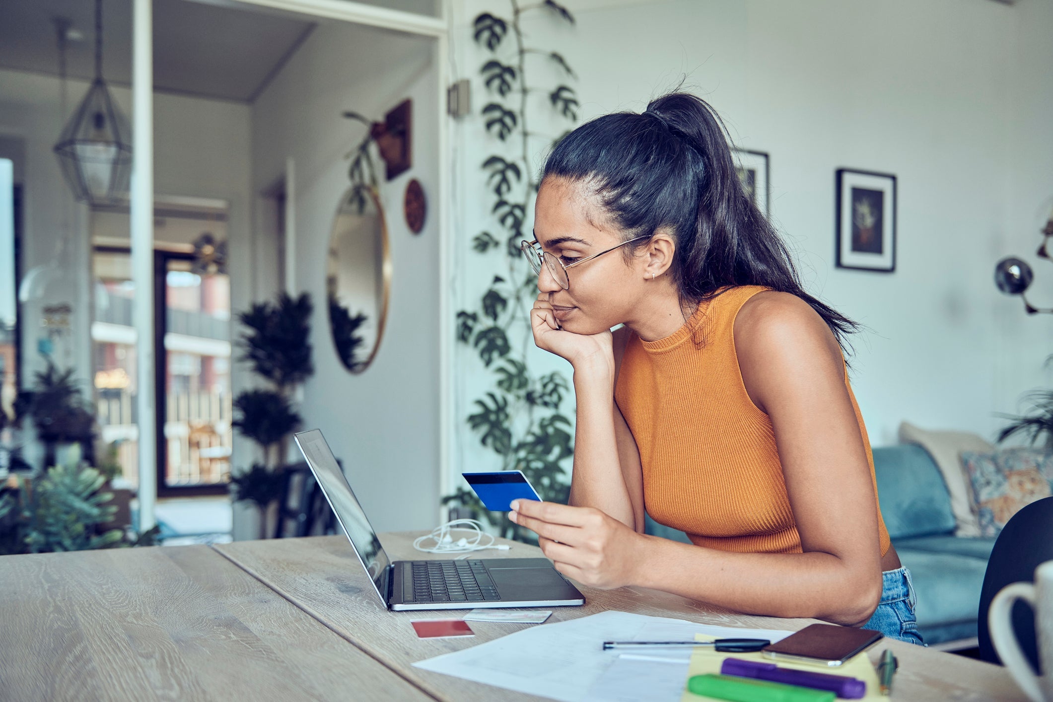 Woman looking at laptop with credit card in hand
