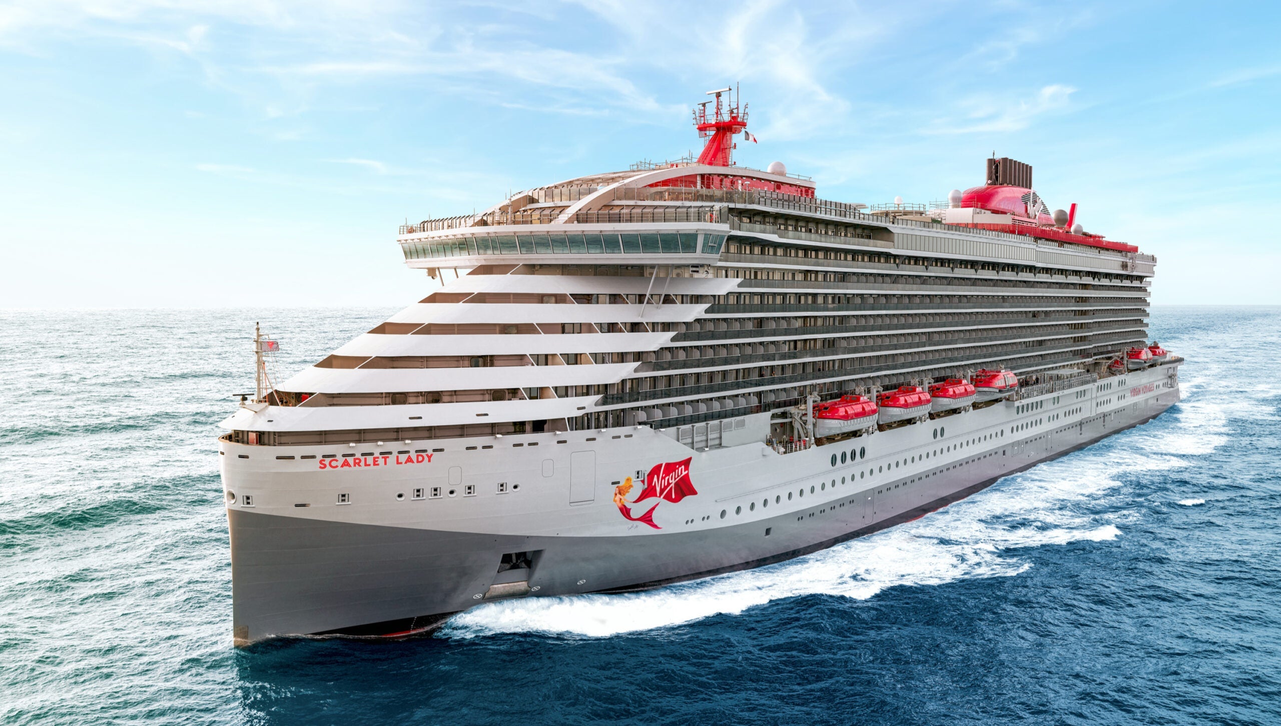 A Virgin Voyages cruise ship sailing on blue water with a blue sky in the background