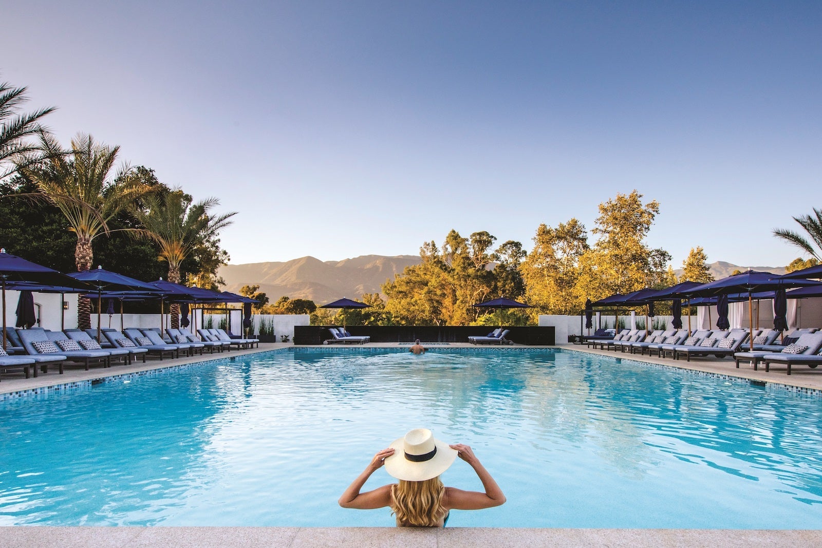 woman wearing hat in swimming pool near the mountains
