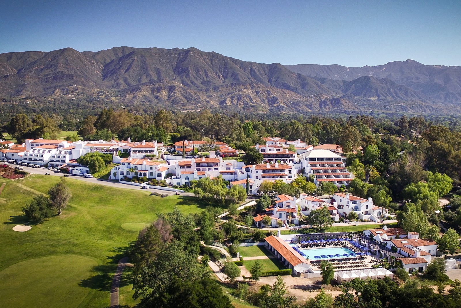 Aerial shot of white resort with red roof, mountains in the background