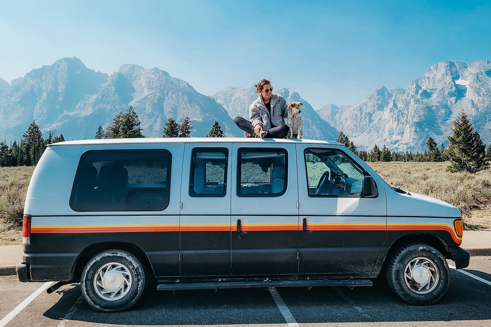 A dog and his owner sitting on top of a van