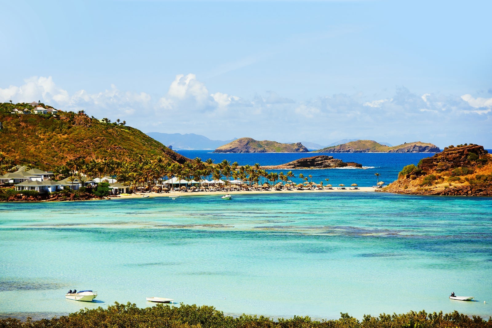 aerial view of turquoise waters and beach resort in front of distant mountains