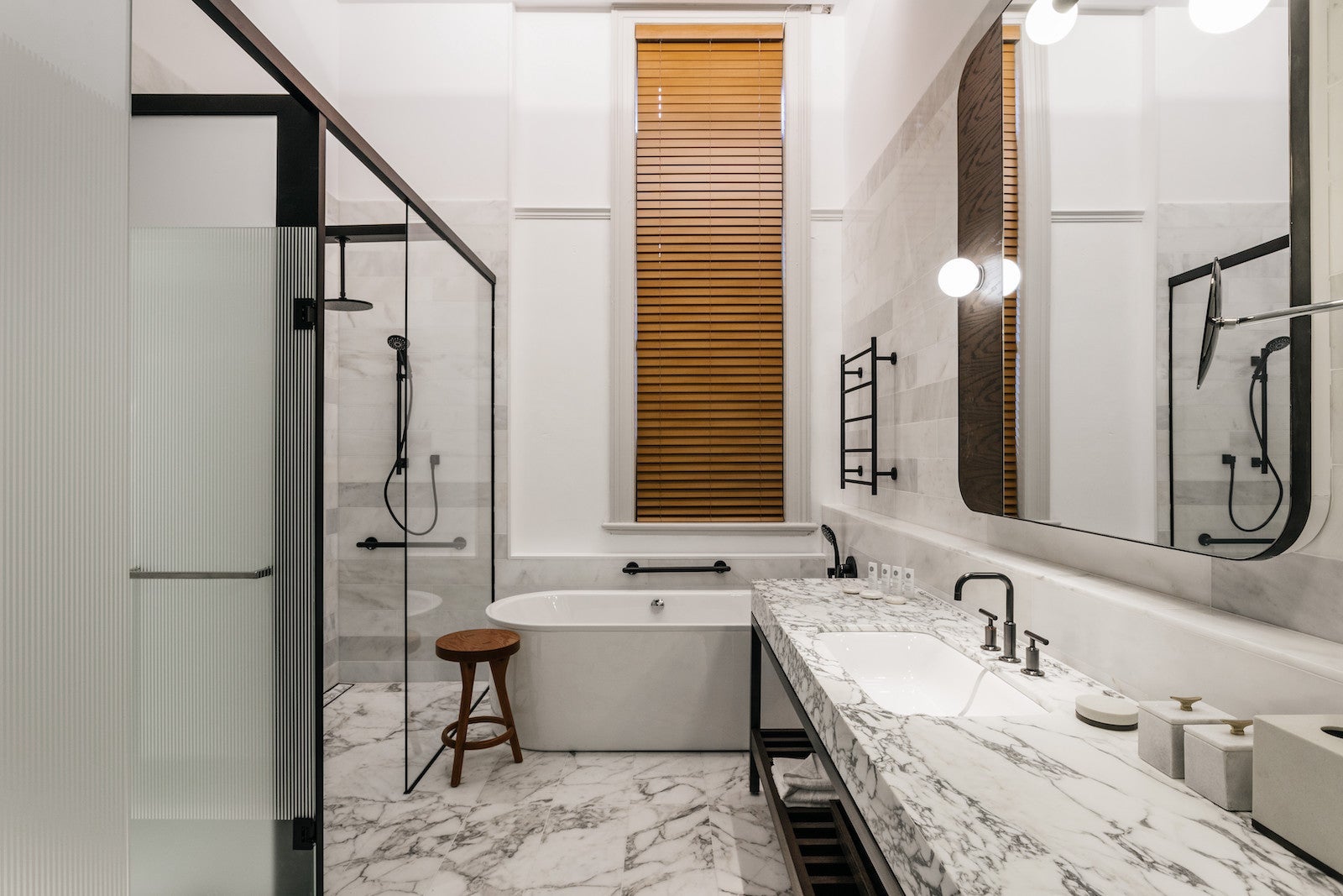 large white marble bathroom with shower, large white bathtub, and large vanity sink and mirror