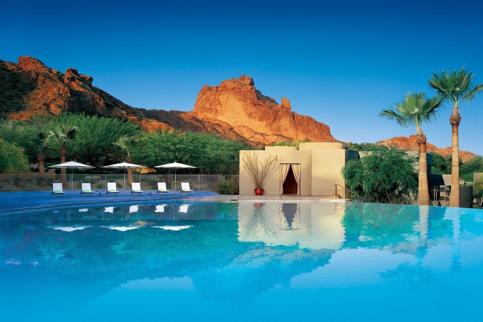 large infinity pool with lounge chairs and cabana near large mountain