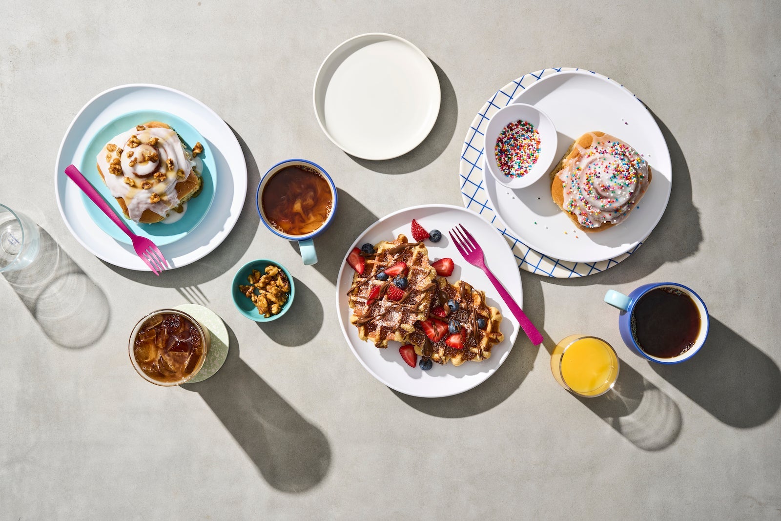 plates of breakfast food including cinnamon rolls and waffles
