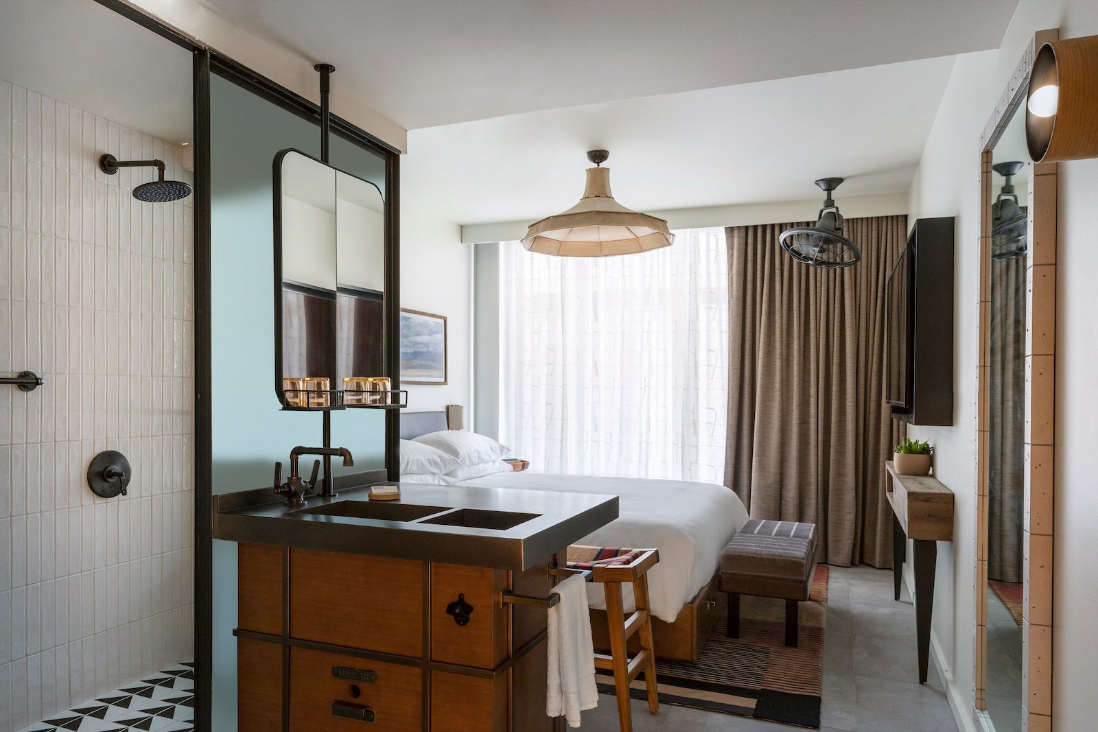 small hotel room with shower, sink and bed