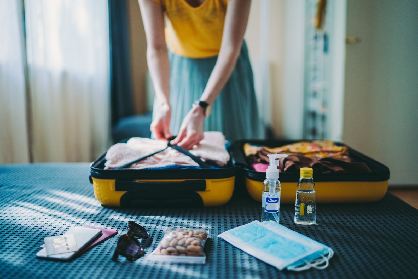 Woman packing yellow carry-on suitcase