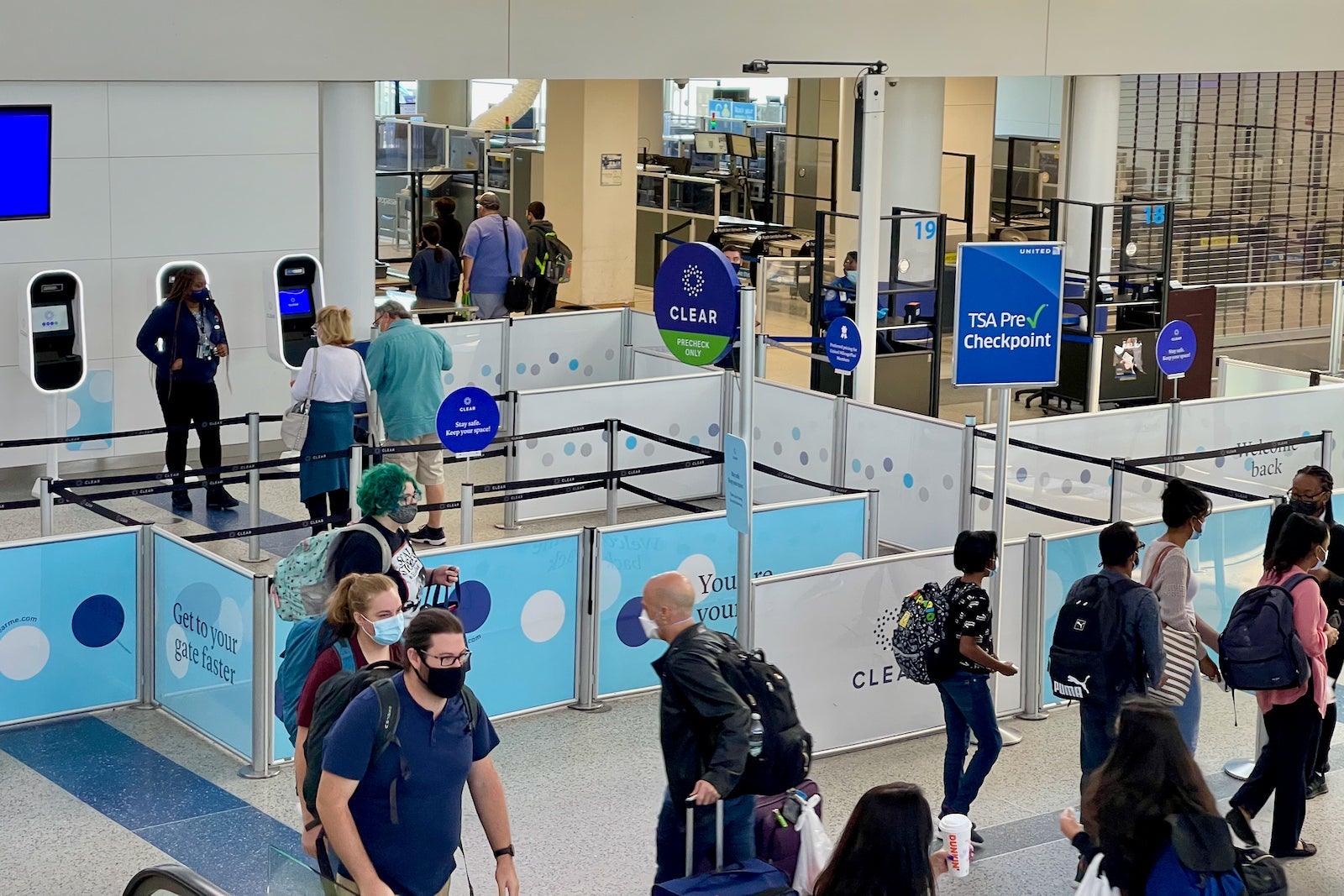 passengers walk past a Clear security checkpoint in the airport