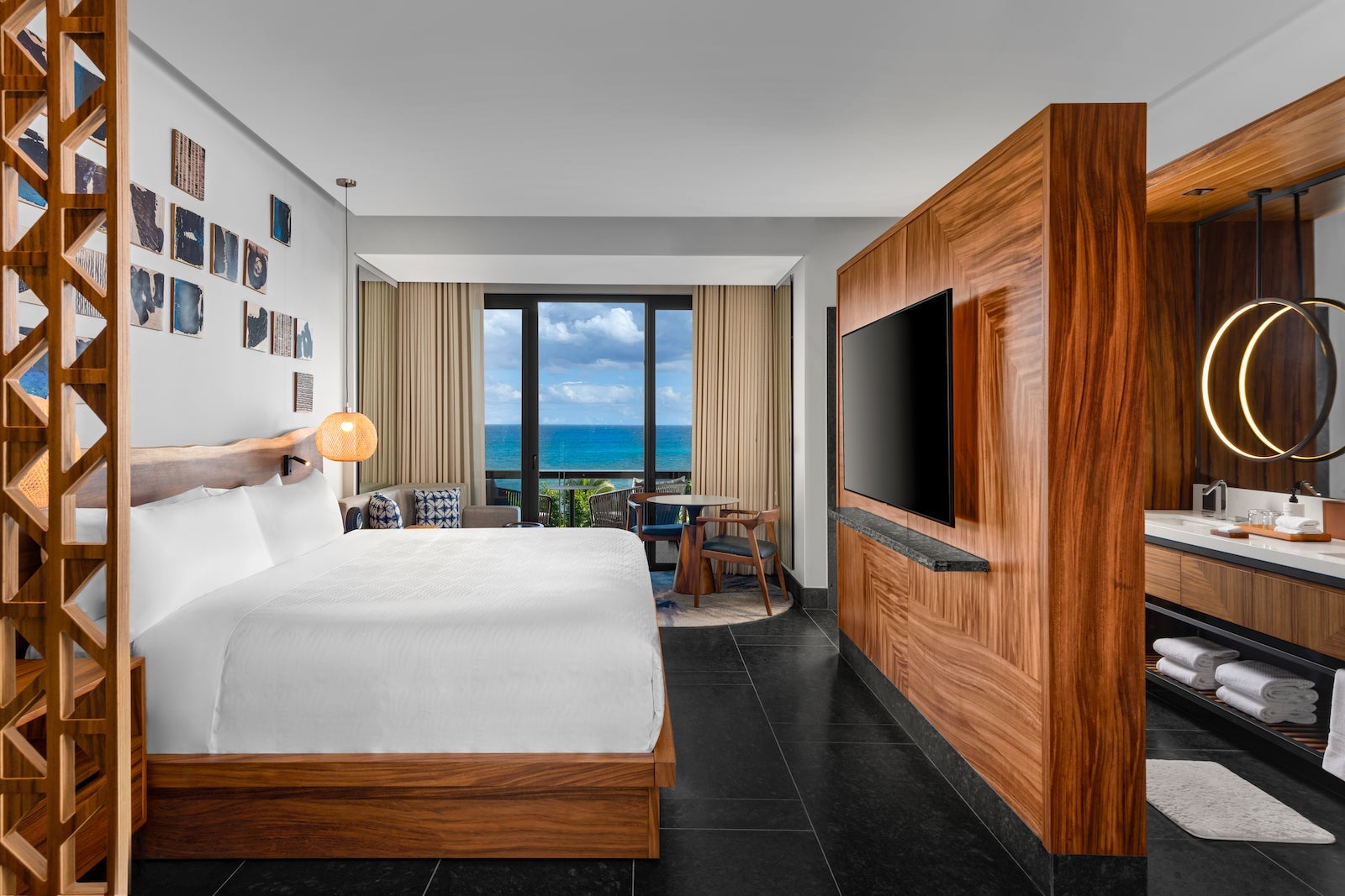 rendering of large hotel room with wooden wall with tv, bed and windows looking out at the ocean