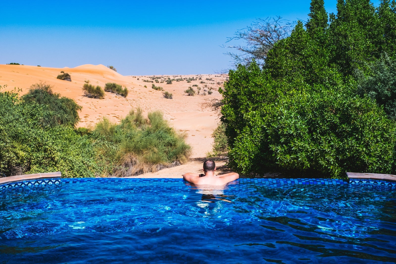 man in plunge pool overlooking desert