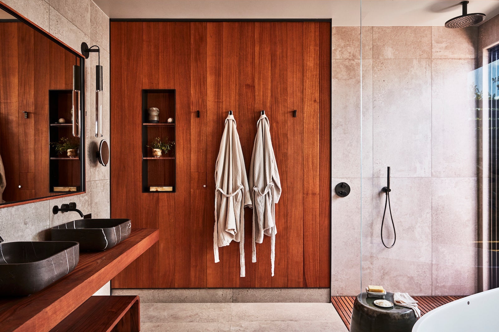 large bathroom with two bathrobes hanging on a wooden wall next to an open shower