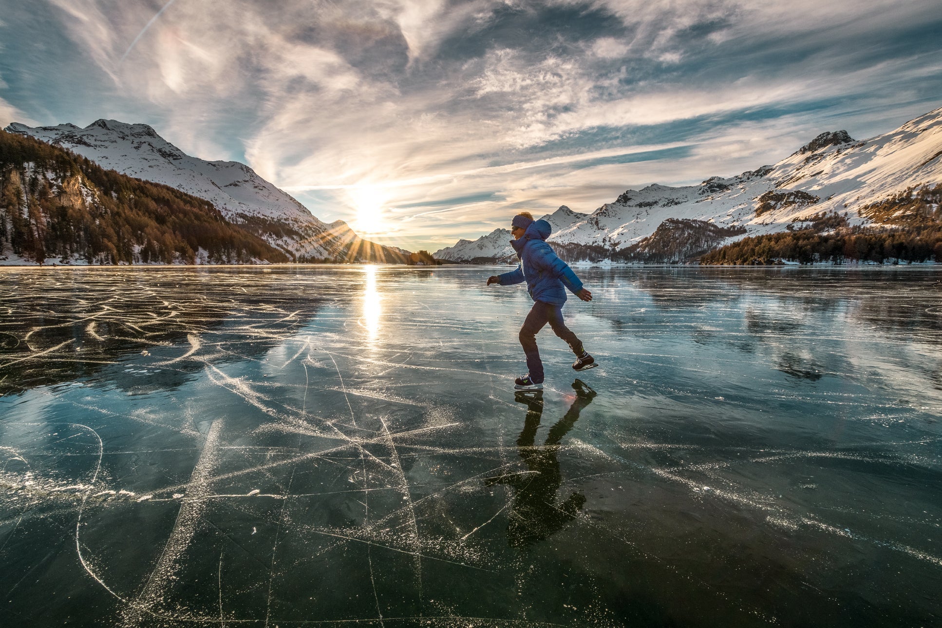 Ice skater on the frozen Lake Sils. The sun goes down towards Maloja.(Photo courtesy Swiss Tourism)
