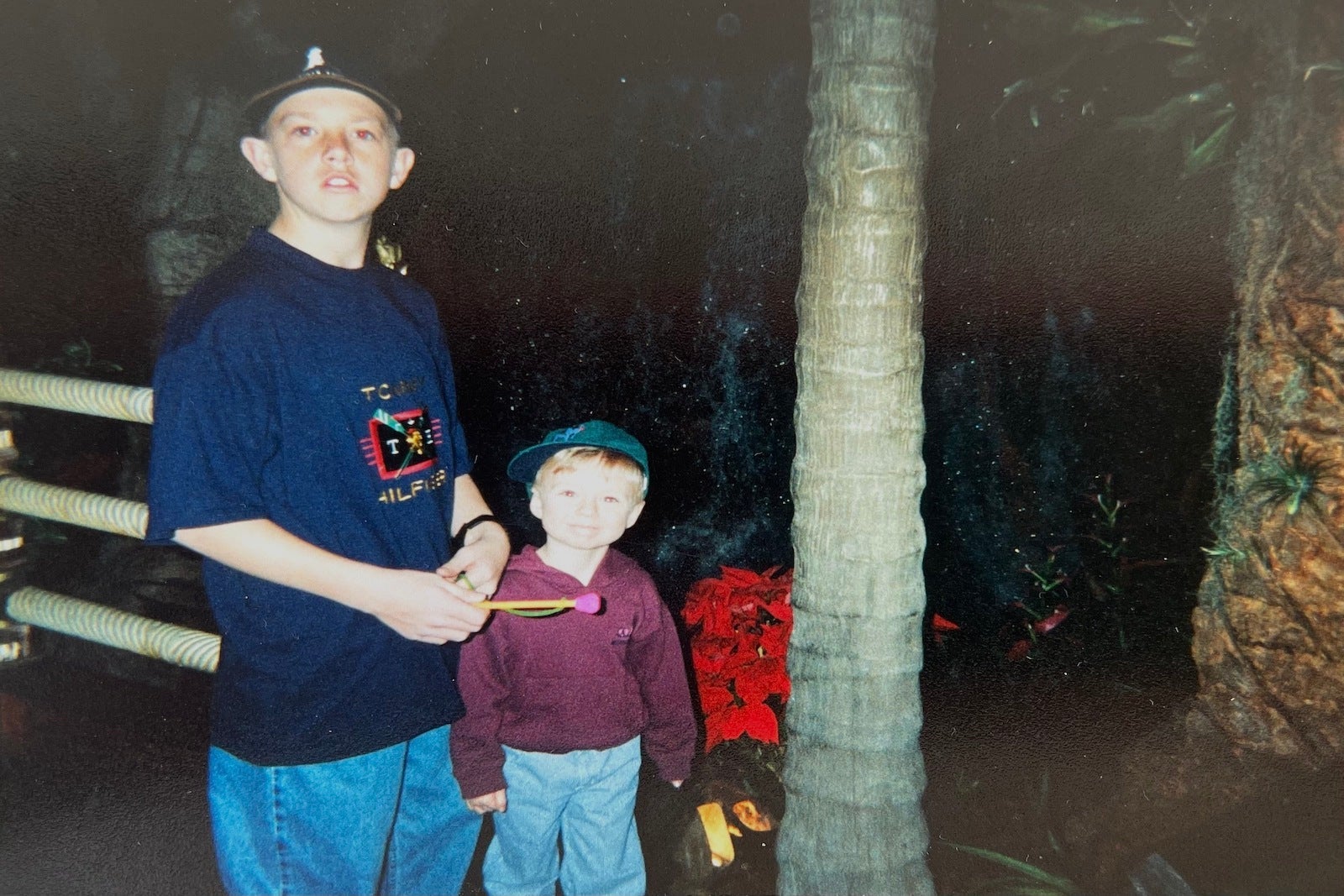 teenage boy and little boy standing in front of palm tree