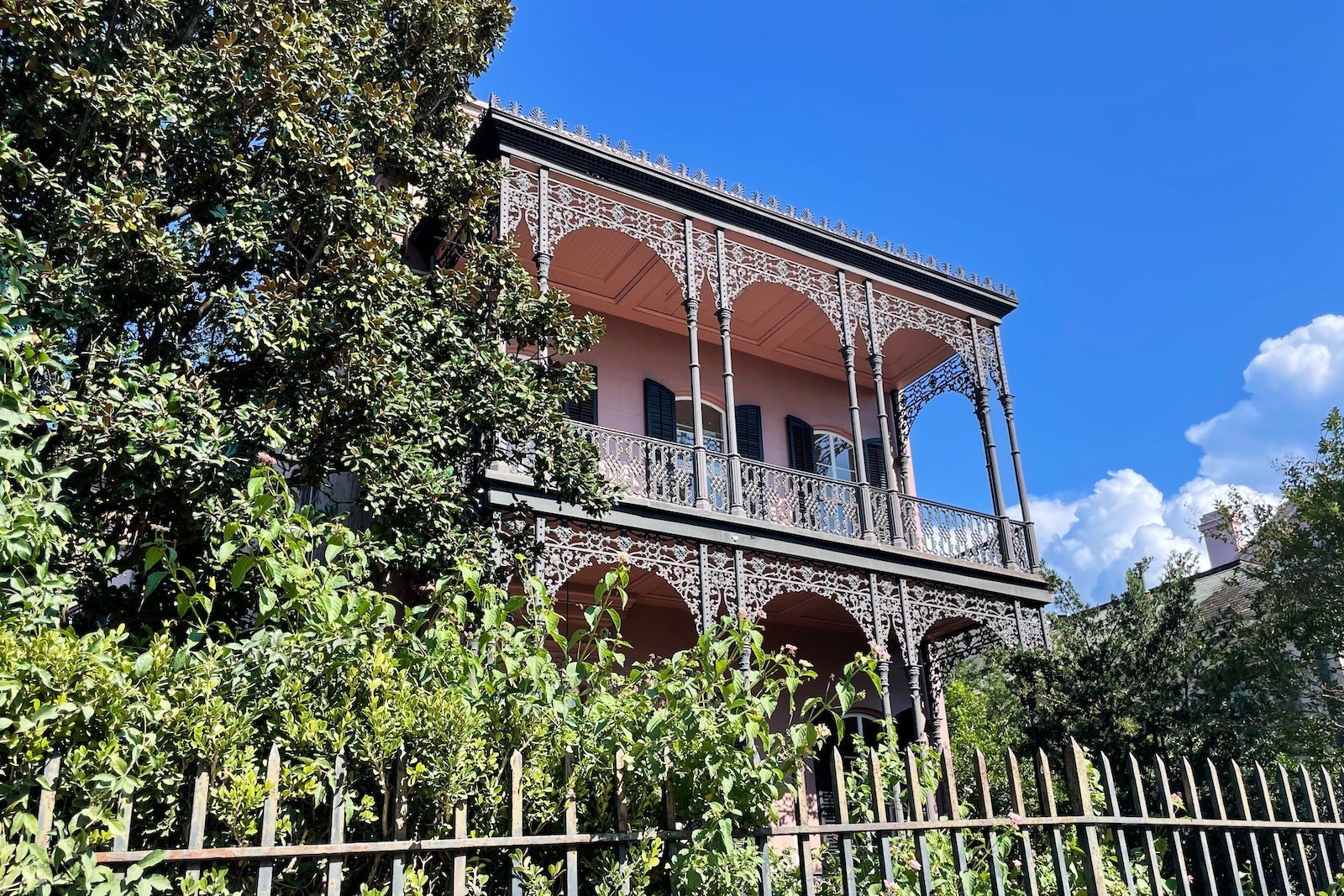 pink house with metal decorations surrounded by plants