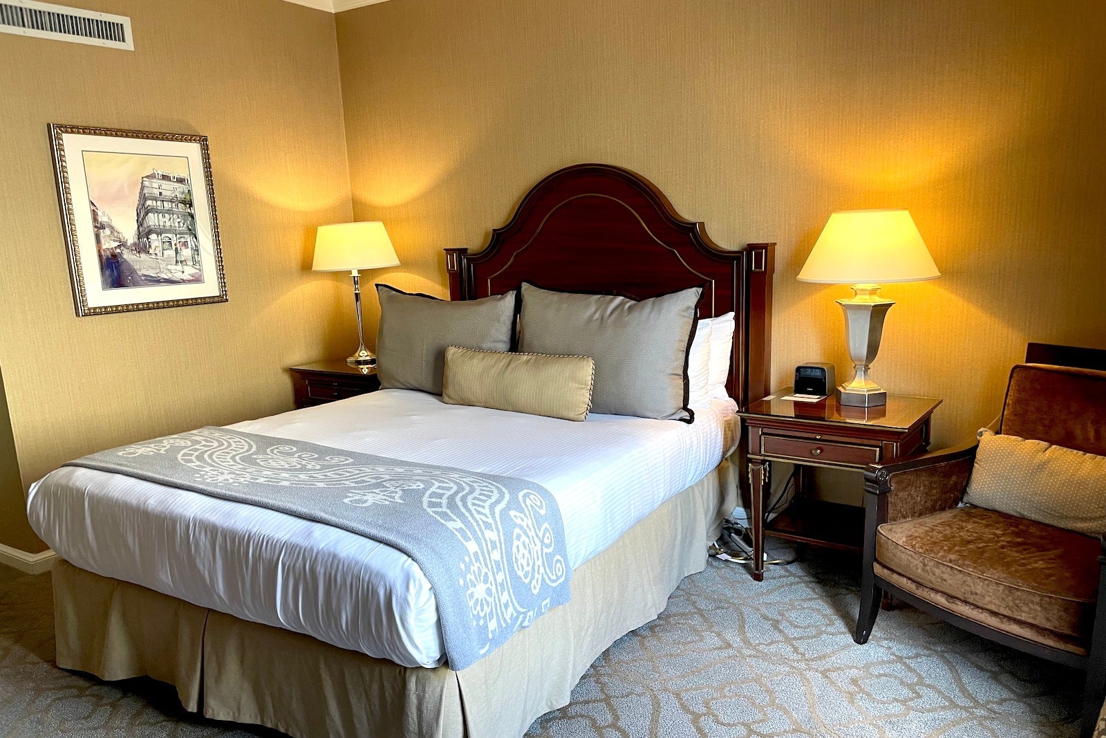 small hotel room with bed, lamps and chair