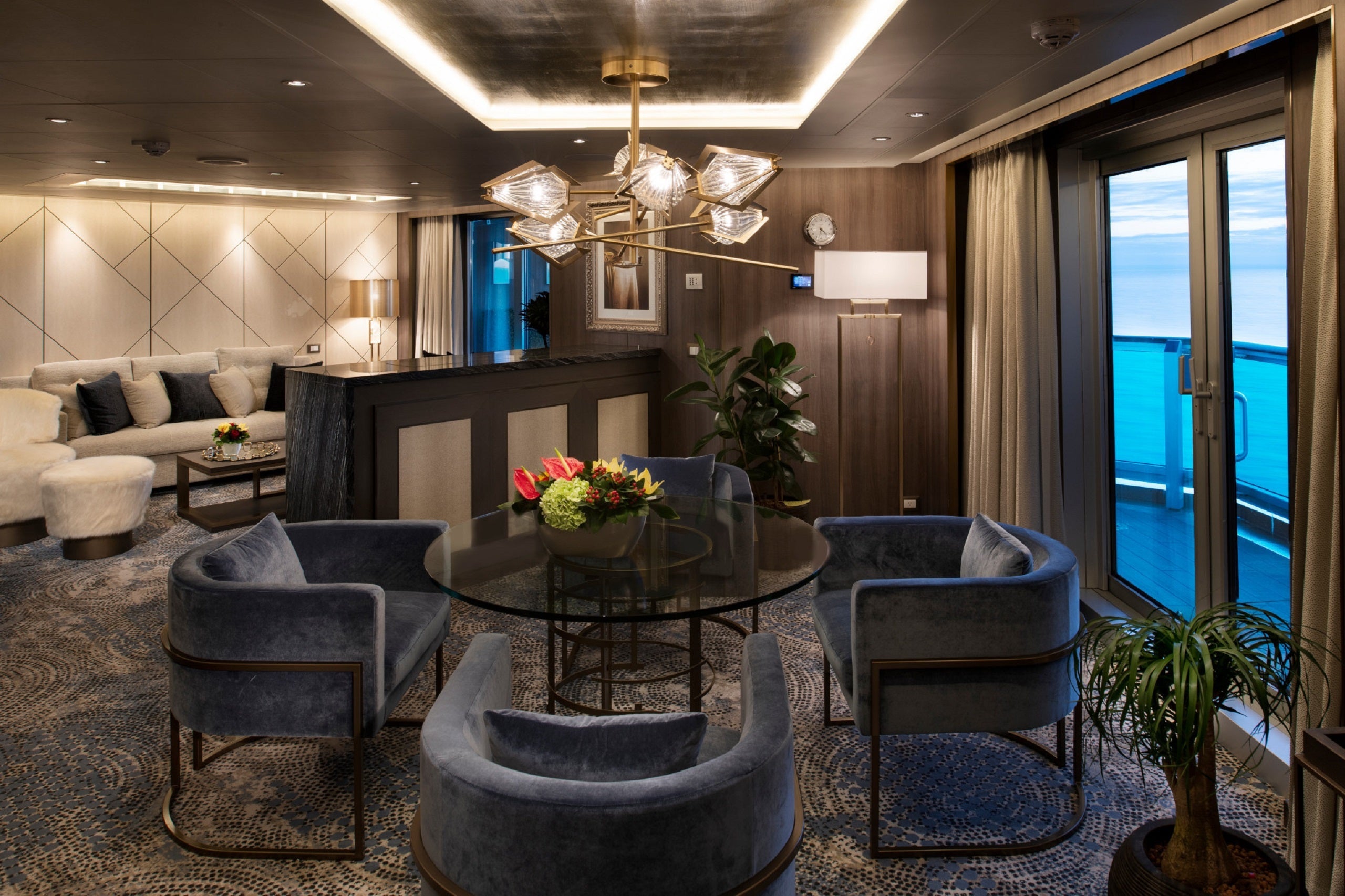 A fancy living room a in a cruise ship suite offers a sofa, coffee table and a dining table with chairs.