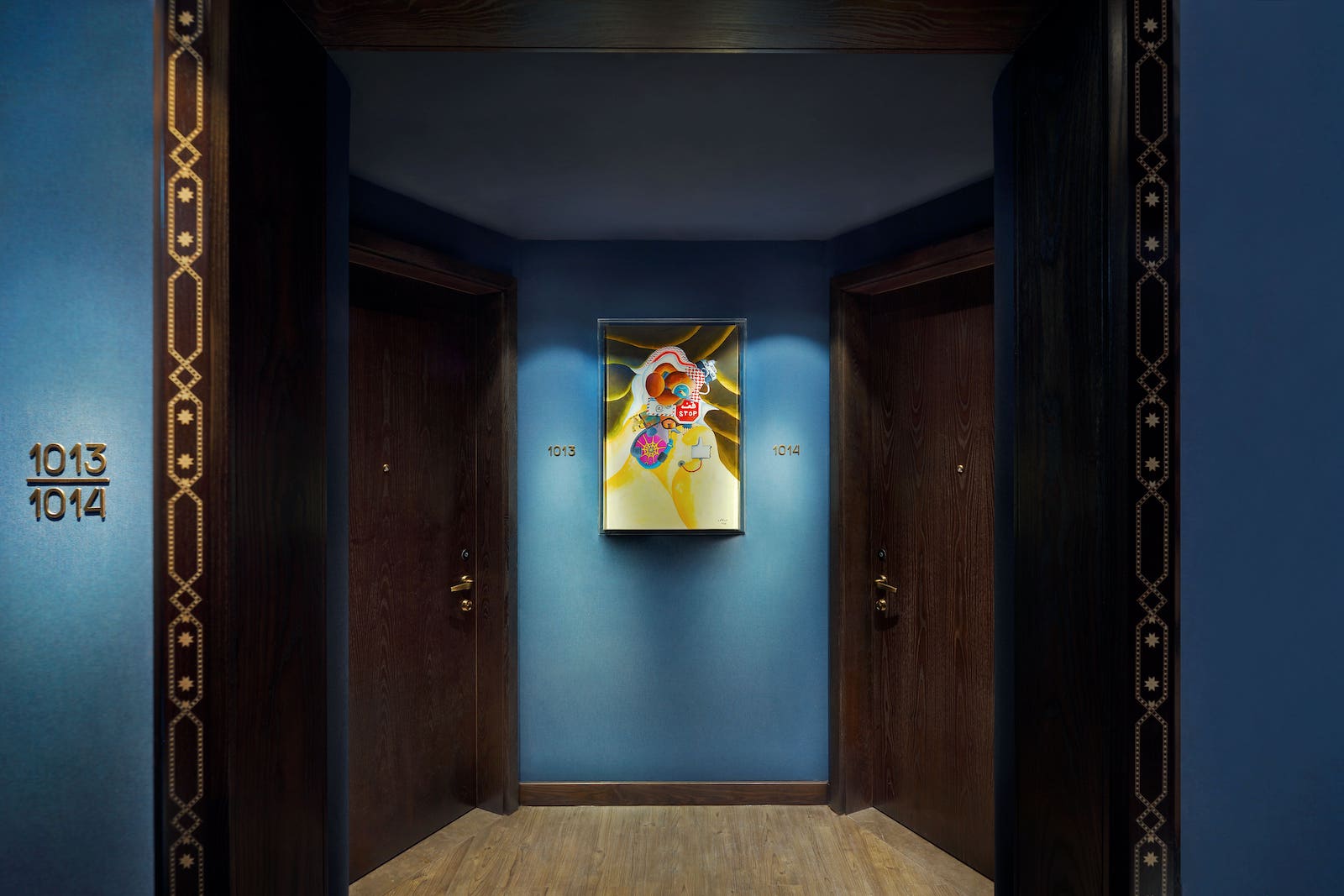 blue walls with two brown hotel doors and art