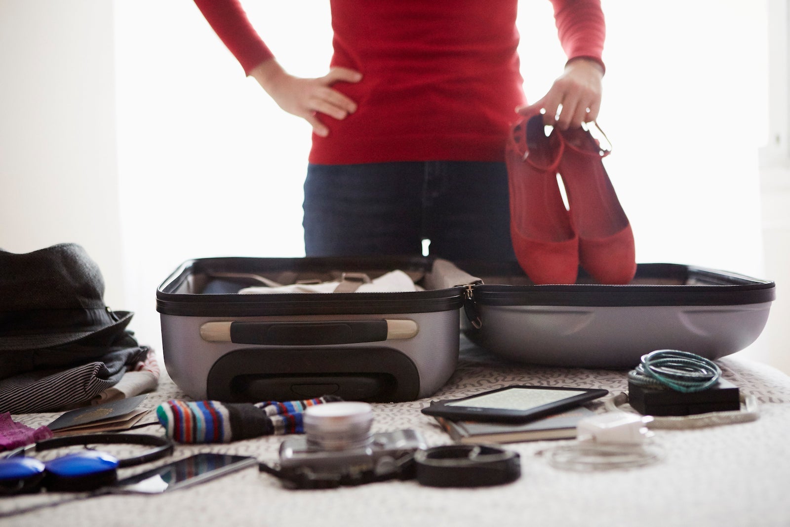 Woman packing suitcase, holding shoes